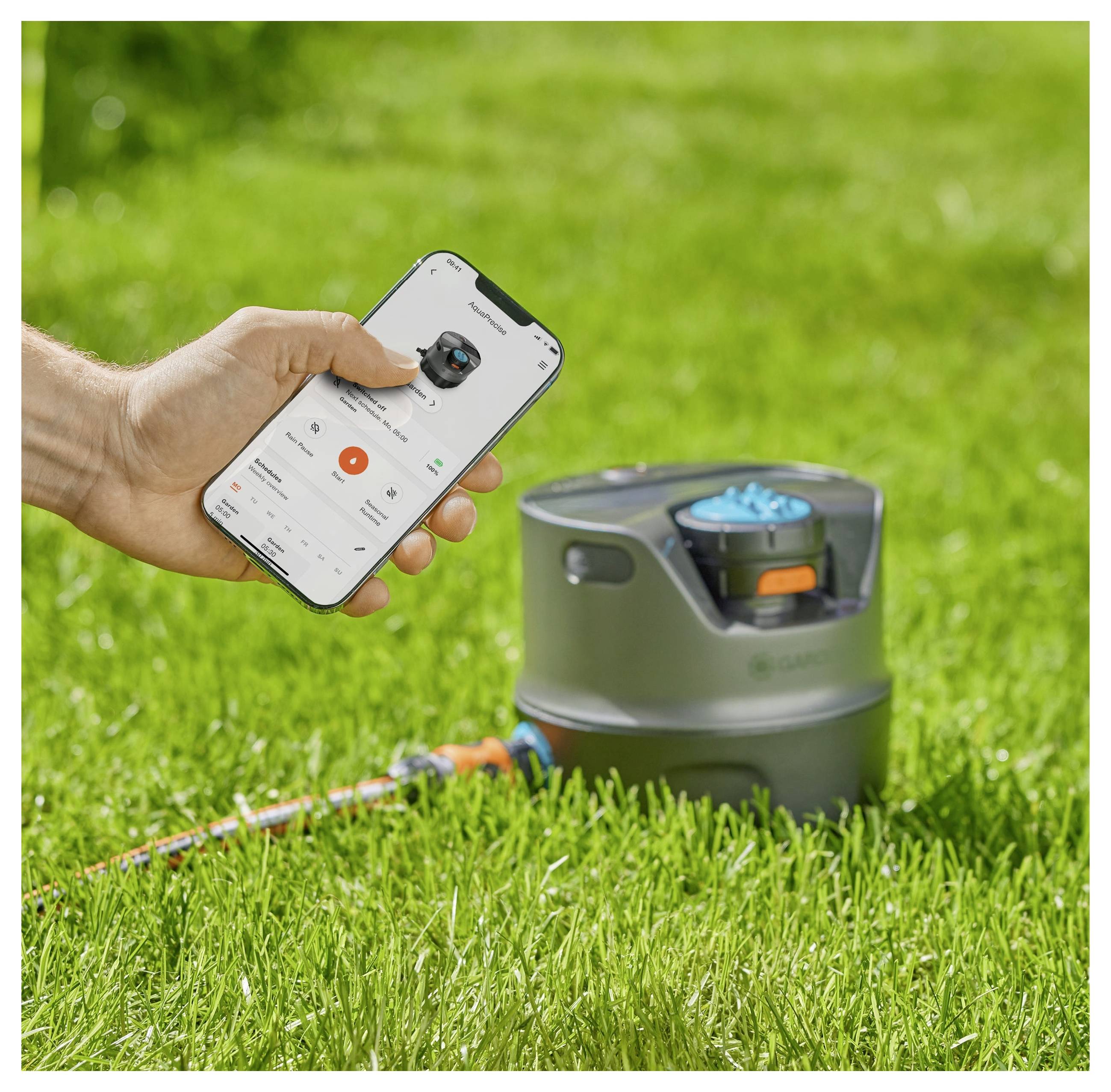 Une personne utilise une application mobile pour contrôler un système d'arrosage sur une pelouse verte.