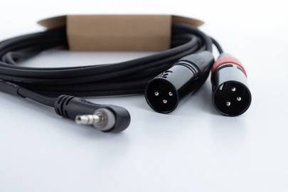 Câble audio noir avec deux connecteurs XLR et une fiche jack 3,5 mm, utilisé pour connecter des appareils audio.