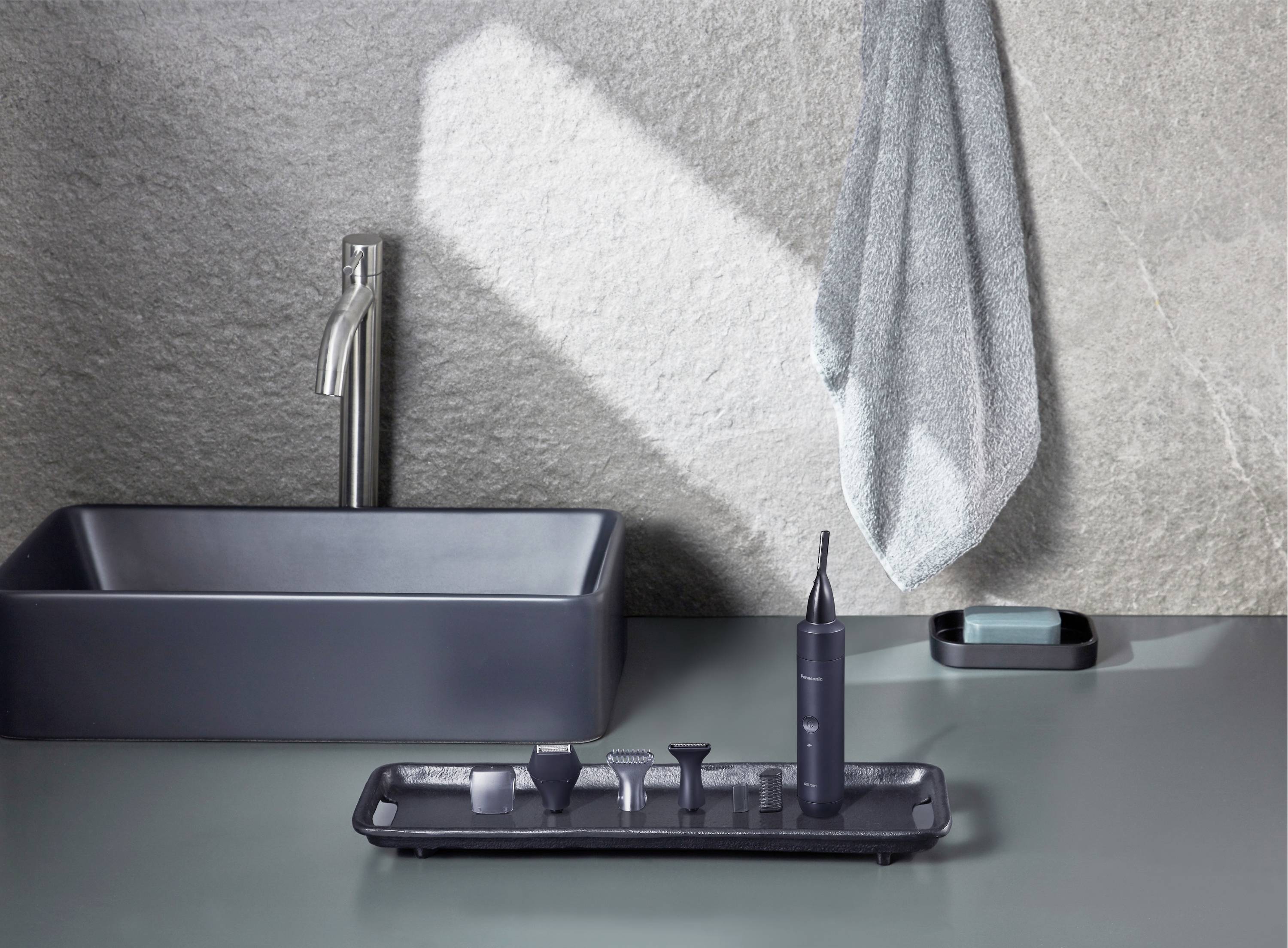 Une salle de bain élégamment aménagée avec un lavabo moderne, un appareil de nettoyage dentaire et une serviette suspendue au mur.