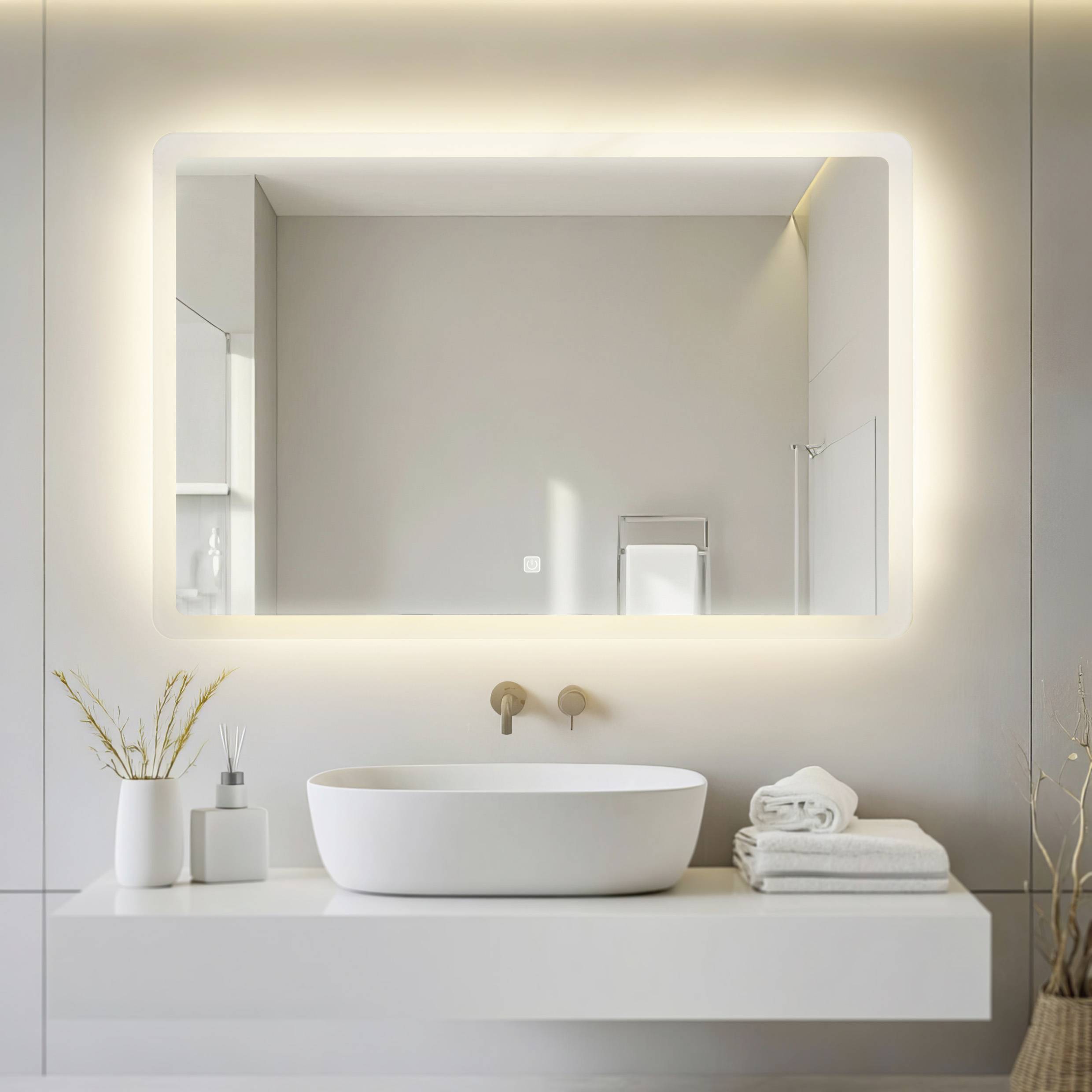Une salle de bain moderne avec un miroir éclairé au-dessus d'un lavabo blanc et deux serviettes sur l'étagère.