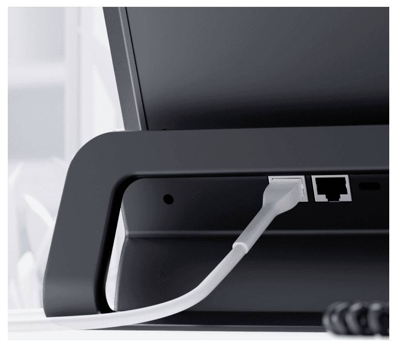 Un câble blanc est branché dans le port LAN d'un moniteur noir posé sur un bureau.