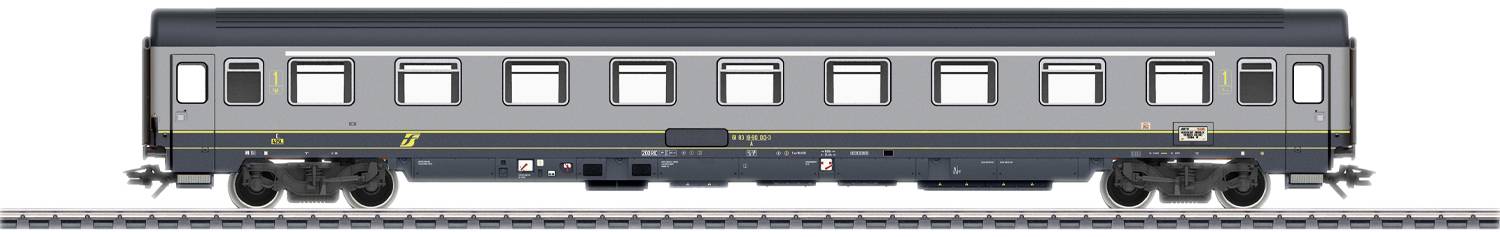 Un wagon de train gris est stationné sur les rails, avec des lignes jaunes et plusieurs fenêtres de chaque côté. Le wagon a un design moderne.