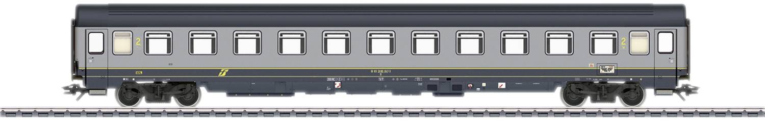 Un wagon de passagers gris sur une voie ferrée. Le wagon a plusieurs fenêtres et une bande jaune le long de son côté.