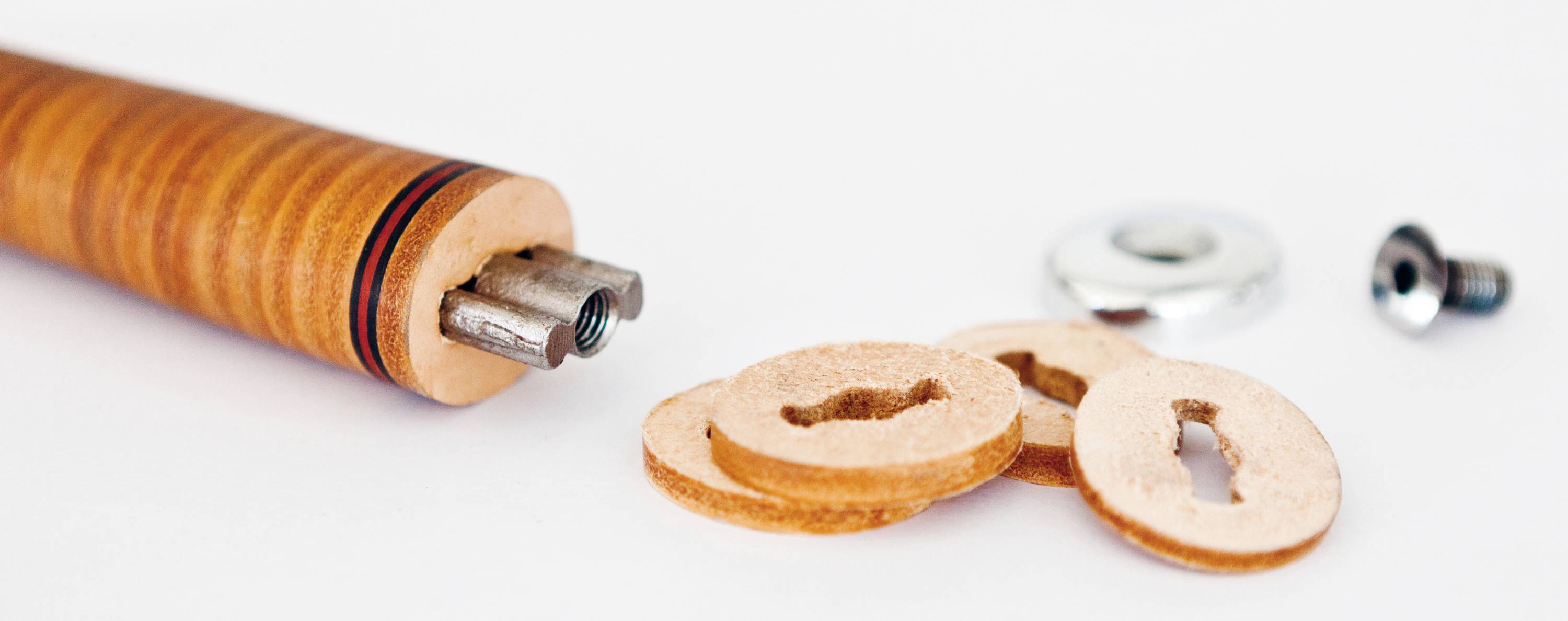Un outil artisanal en bois avec des joints en cuir, une plaque métallique et une vis sur un fond blanc. Utilisé pour l'étanchéité.