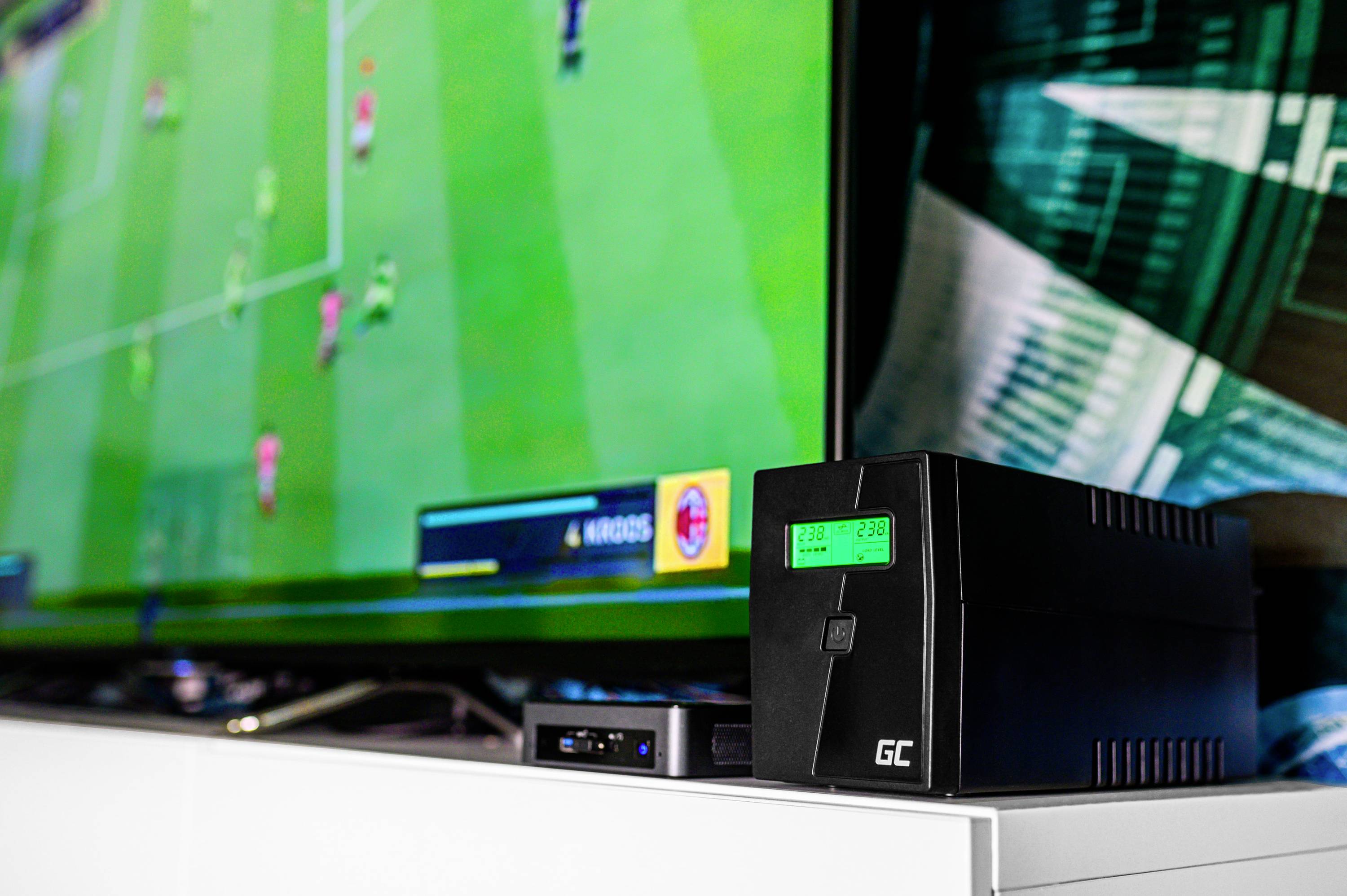 Un téléviseur affiche un jeu vidéo de football. À côté se trouve un onduleur (ASI) avec un affichage lumineux.