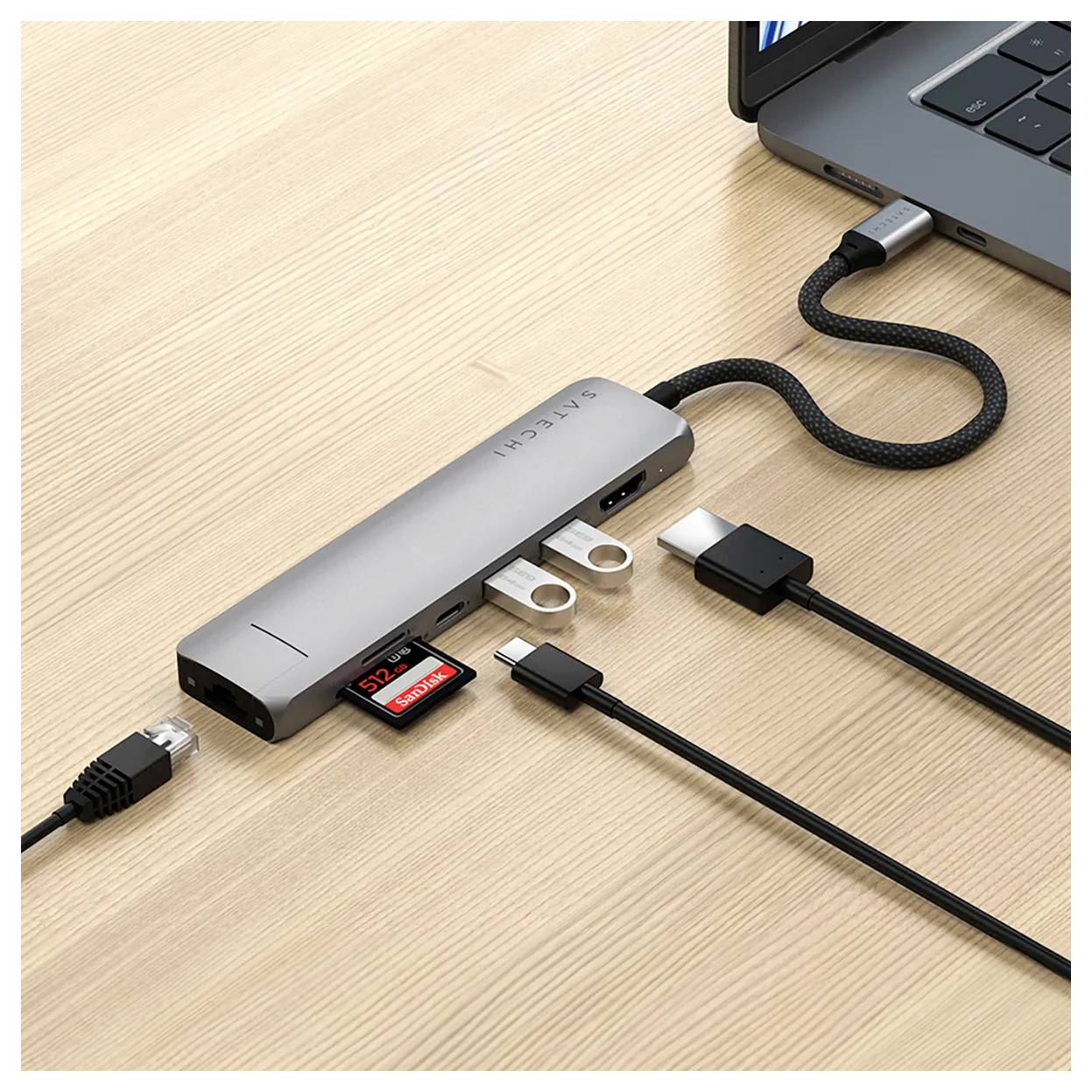 Un hub USB-C est connecté à un ordinateur portable. Plusieurs câbles et une carte SD y sont branchés. Il permet de raccorder des appareils supplémentaires.