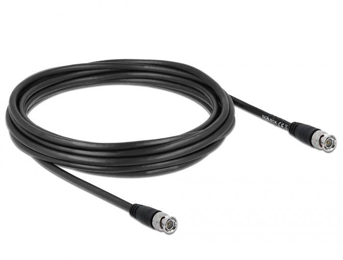 Un câble coaxial noir avec deux fiches à ses extrémités, enroulé sur une surface.