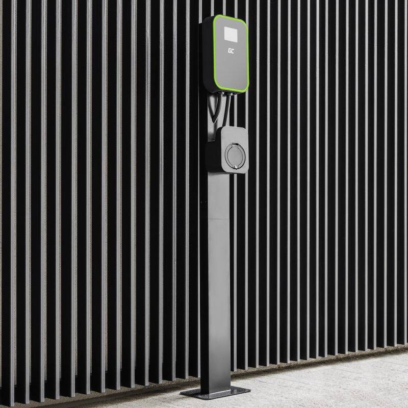 Une station de charge noire pour voitures électriques devant un mur rayé, avec un contour vert autour de l'écran.