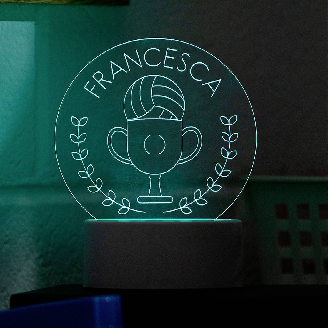 Trophée en acrylique lumineux portant le nom 'Francesca' et orné d'un symbole de coupe gravé, entouré d'une couronne de laurier.