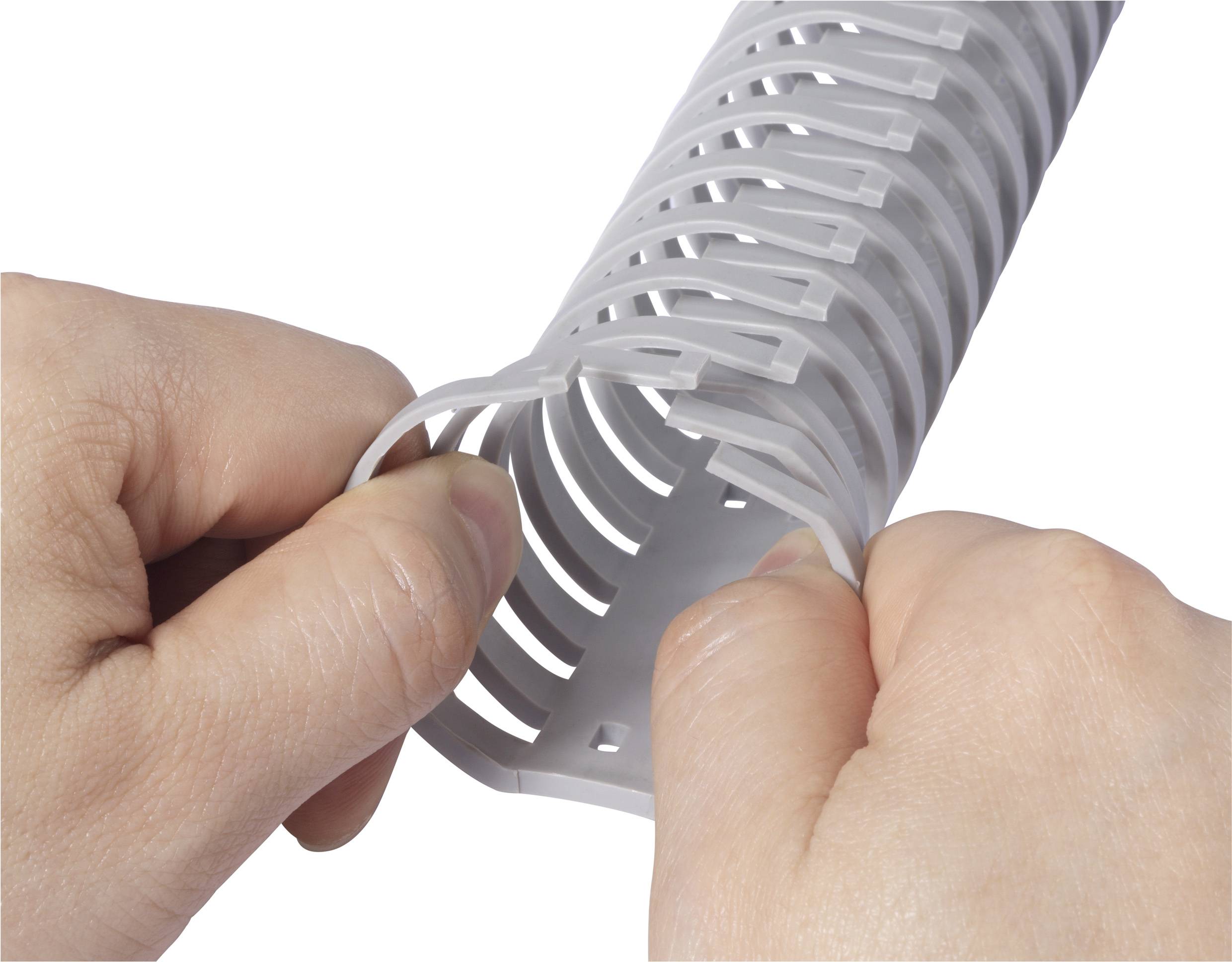 Deux mains plient un conduit de câbles blanc et flexible avec des fentes pour organiser et protéger les câbles.