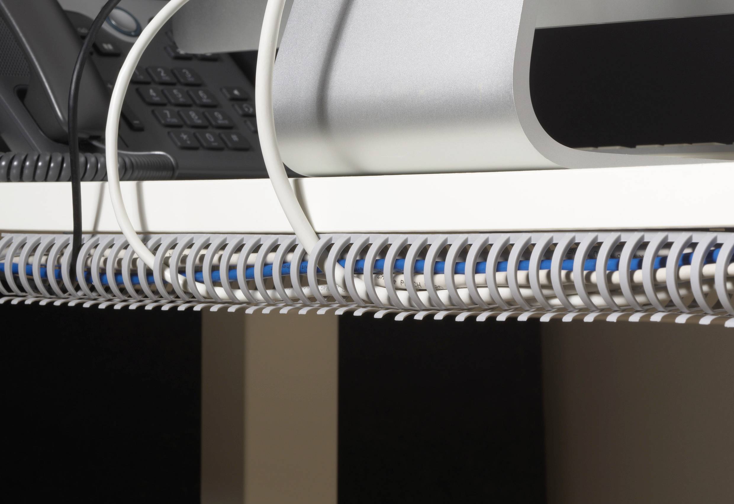 Téléphone et câbles sur un bureau, un système de gestion des câbles maintient les câbles bien rangés.