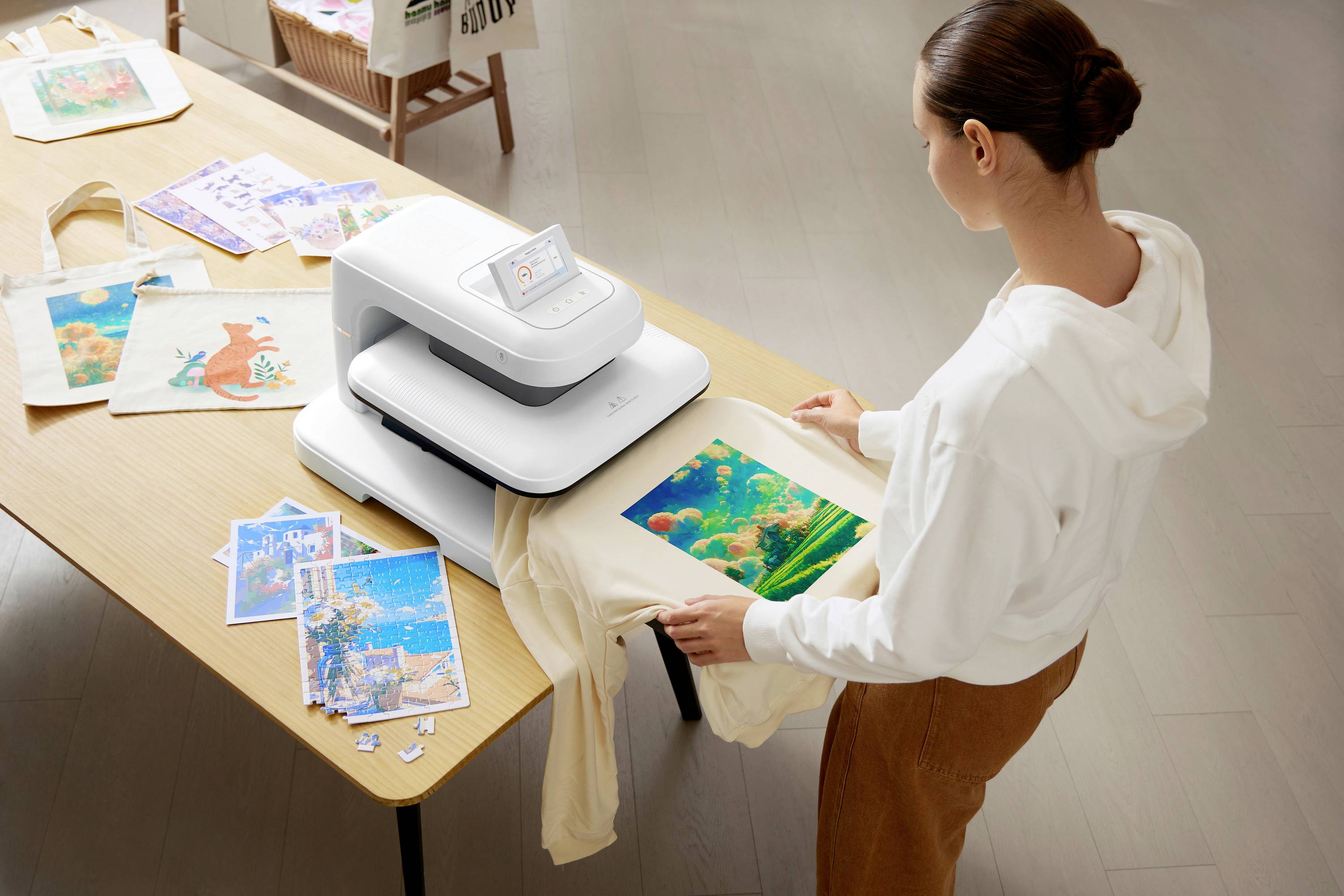 Une femme imprime à l'aide d'une machine un sac en tissu avec une image colorée sous-marine. D'autres matériaux sont posés sur la table.