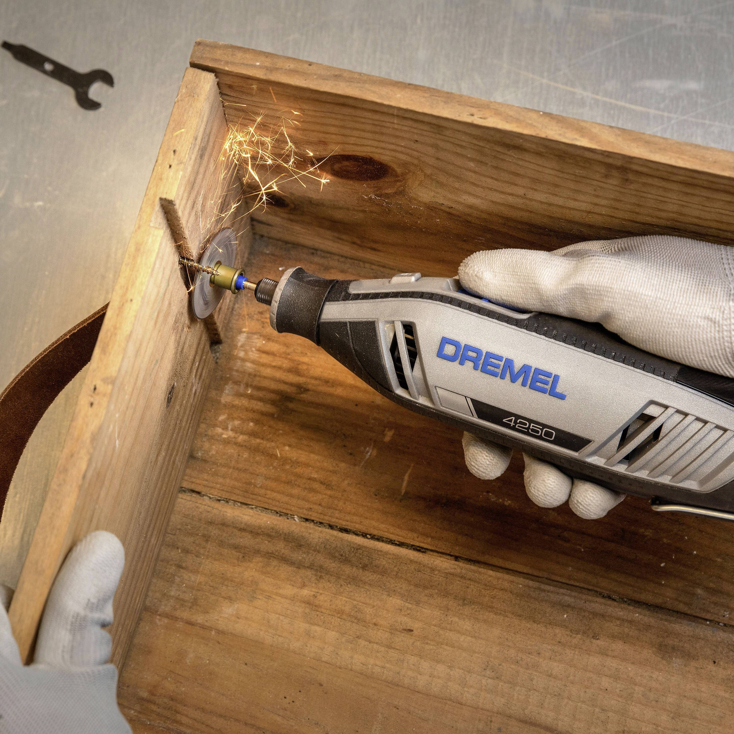 Une personne travaille une boîte en bois avec un outil Dremel. Des étincelles jaillissent de la meule rotative.