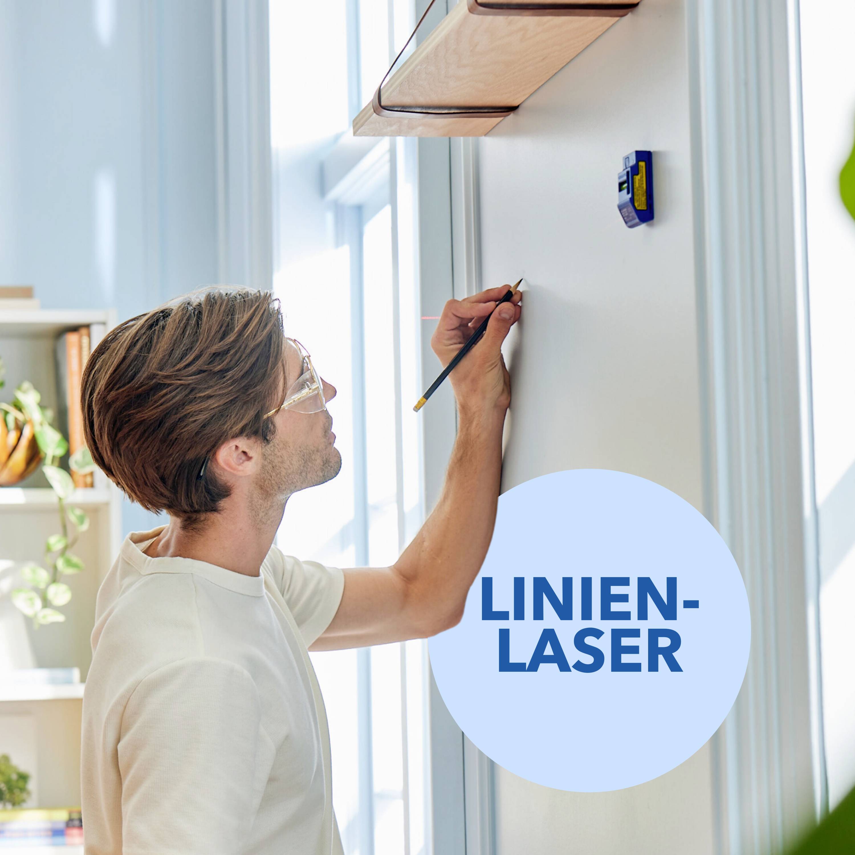 Une personne utilise un laser linéaire pour tracer une ligne droite sur un mur. Des étagères à livres sont visibles en arrière-plan.