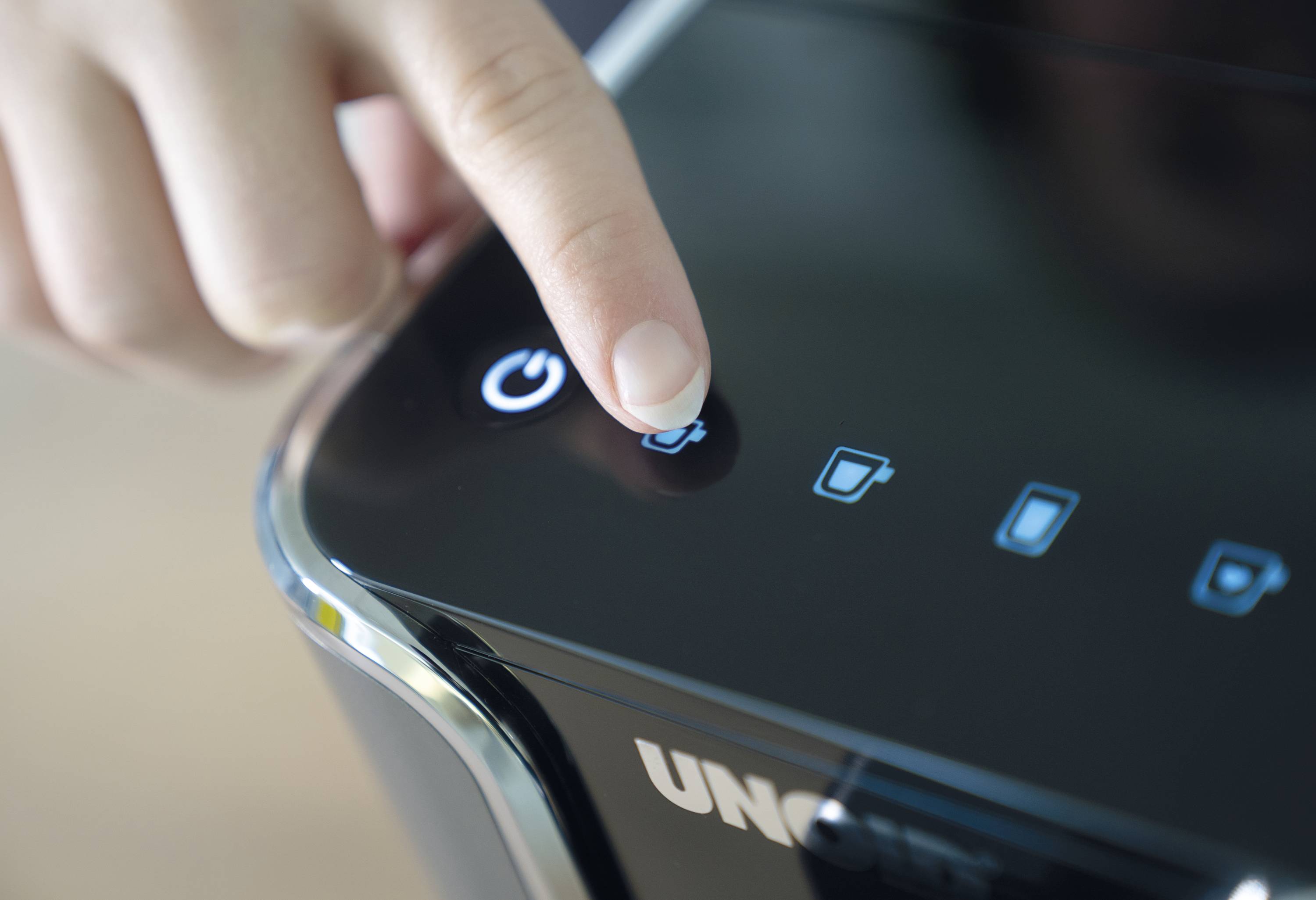 Une main appuie sur le bouton d'alimentation d'un appareil électrique.