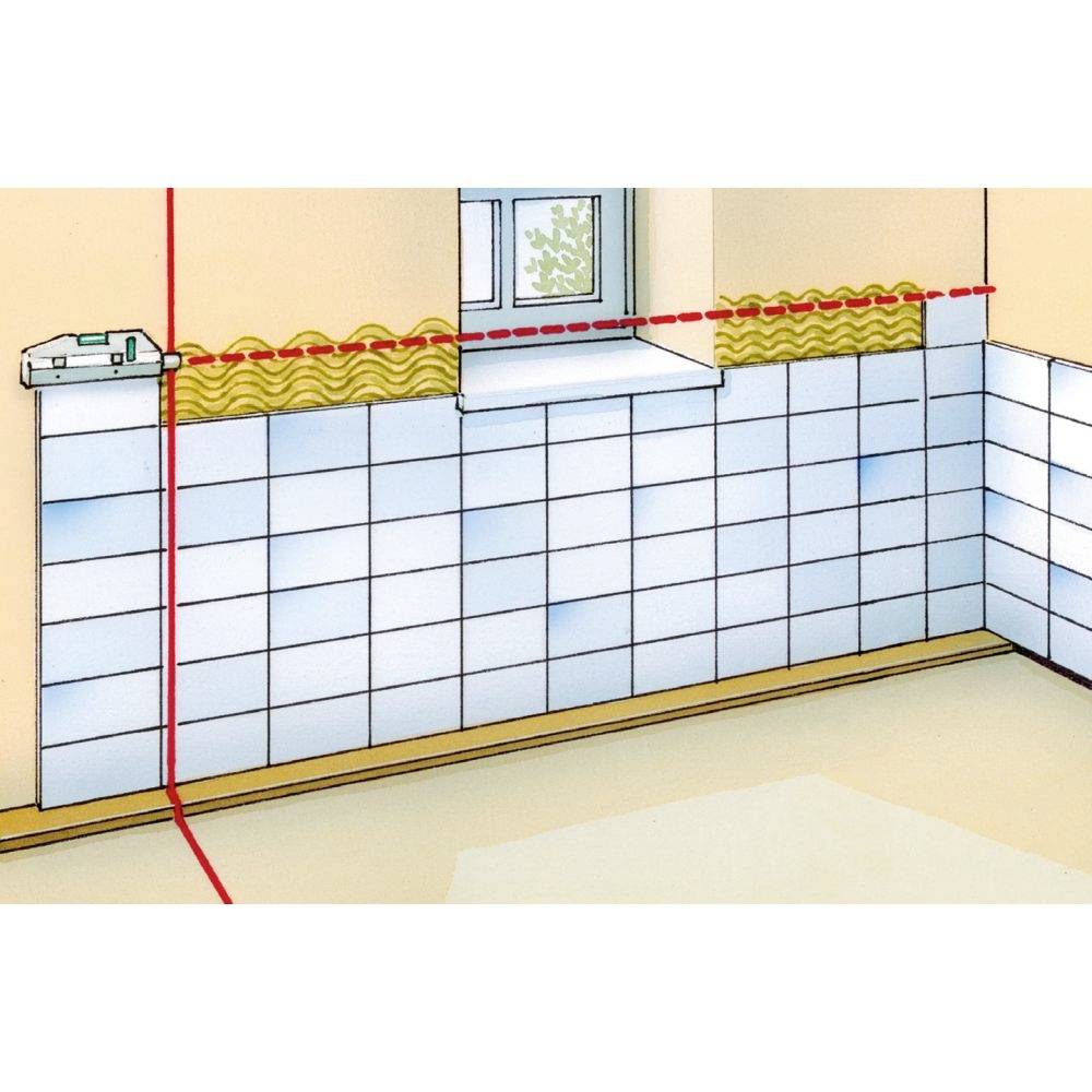 Un mur recouvert de carrelage est aligné. Un faisceau laser marque une ligne horizontale pour une pose précise.