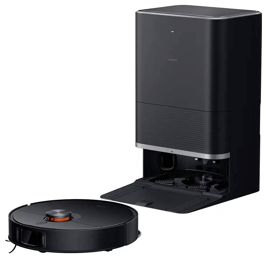 Un robot aspirateur rond noir devant une station de chargement noire servant de réservoir à poussière. Système de nettoyage efficace.