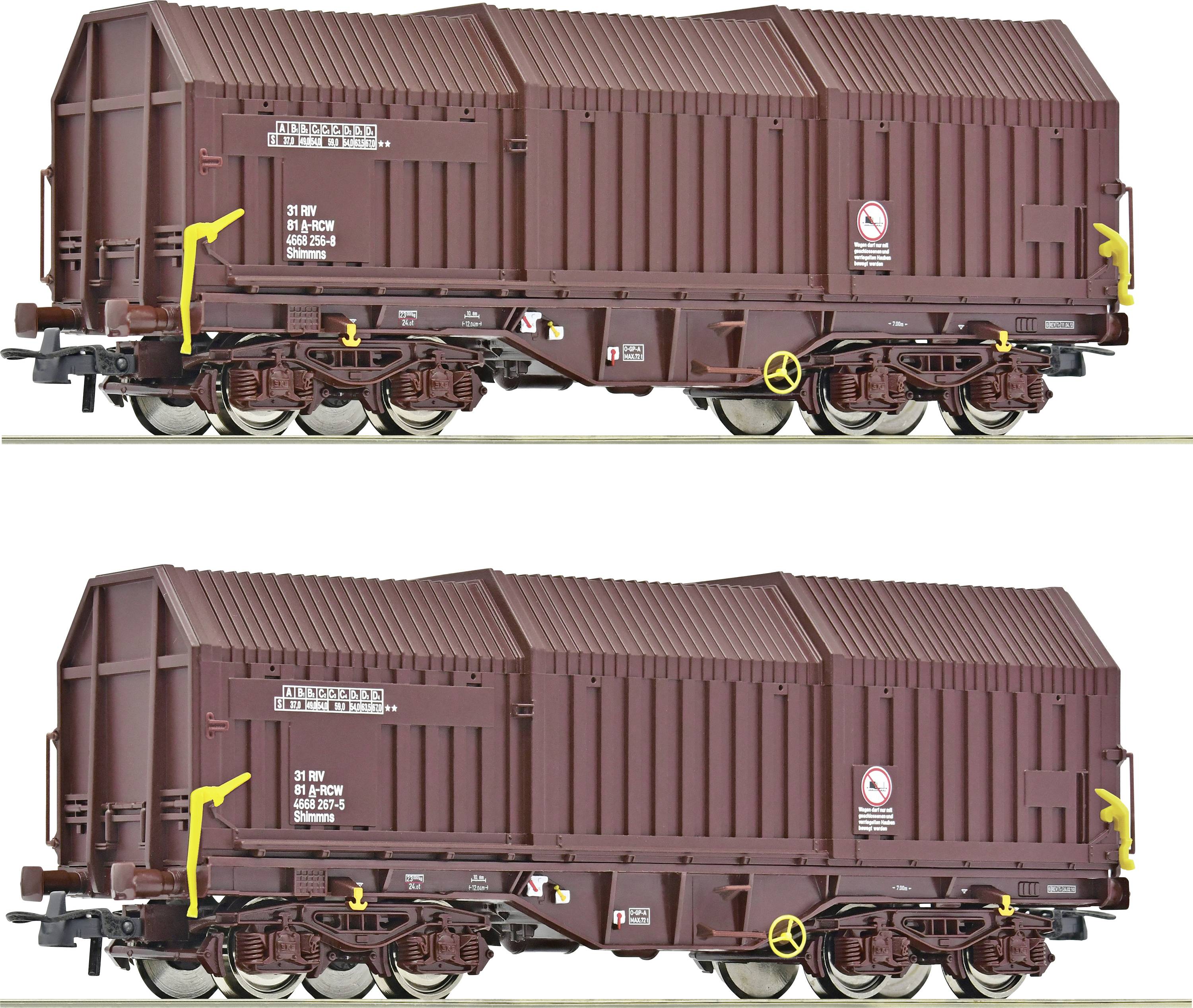 Deux wagons de marchandises identiques, de couleur brune, portant des marquages et des inscriptions latérales, sont stationnés sur une voie ferrée.