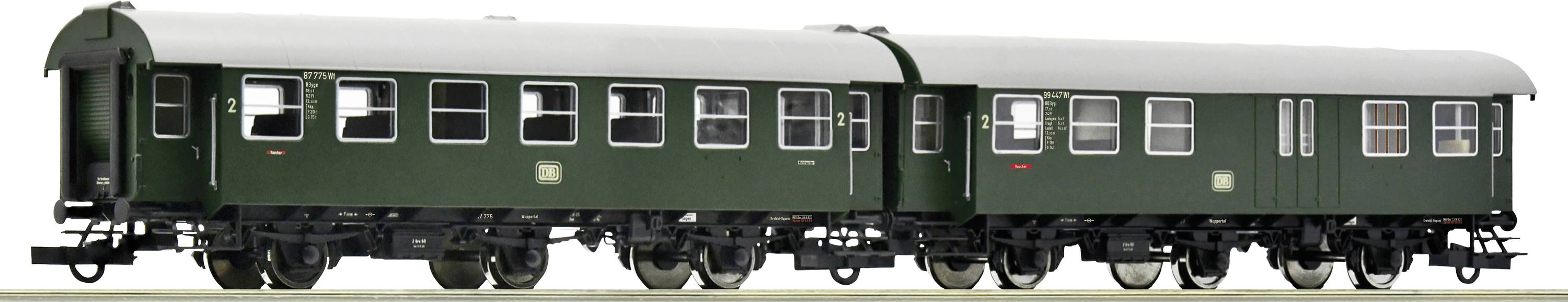 Deux wagons ferroviaires historiques verts, dotés de roues noires, sont alignés côte à côte. Ils présentent plusieurs fenêtres et des renforts métalliques.