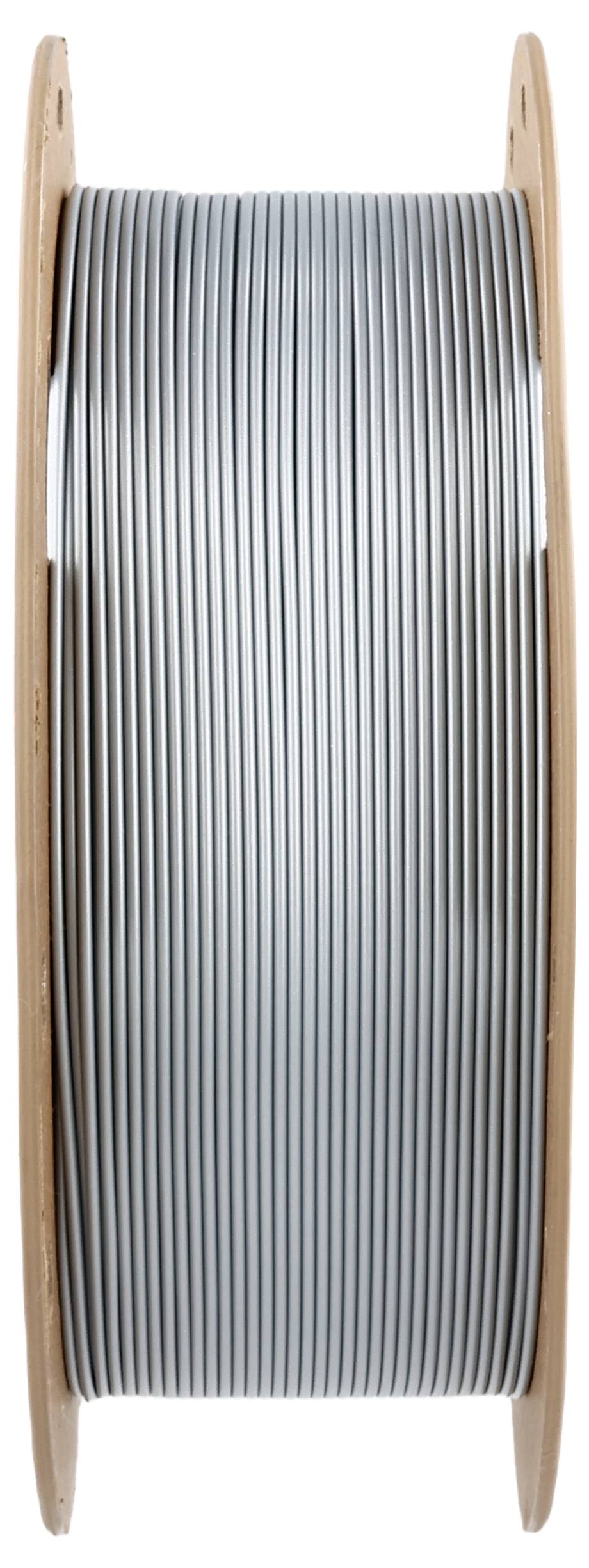 Une bobine dressée verticalement avec un fil d'argent enroulé de manière serrée. Le fil présente une surface lisse et brillante.