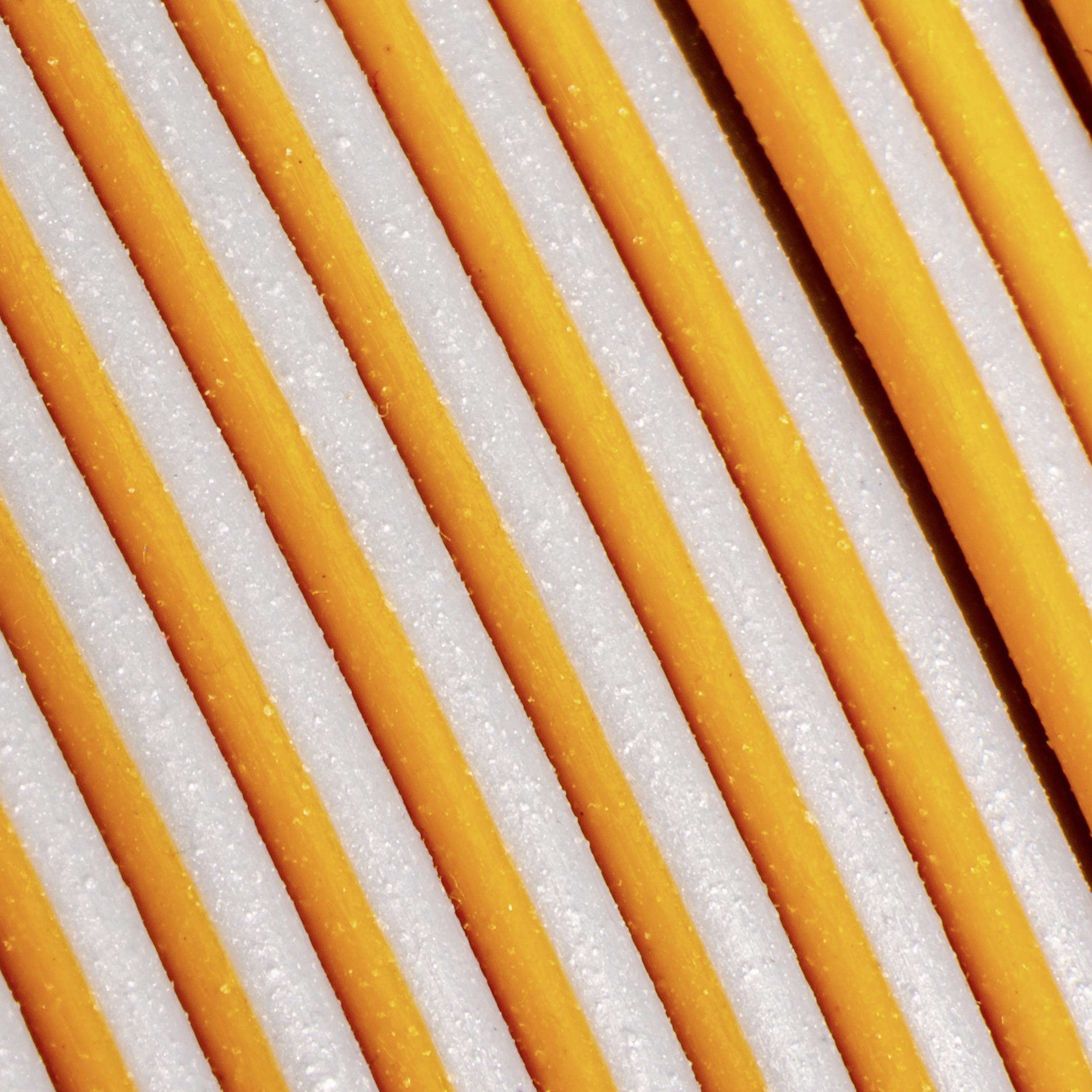 Gros plan de bandes parallèles orange et blanches. La structure rappelle une surface nervurée.