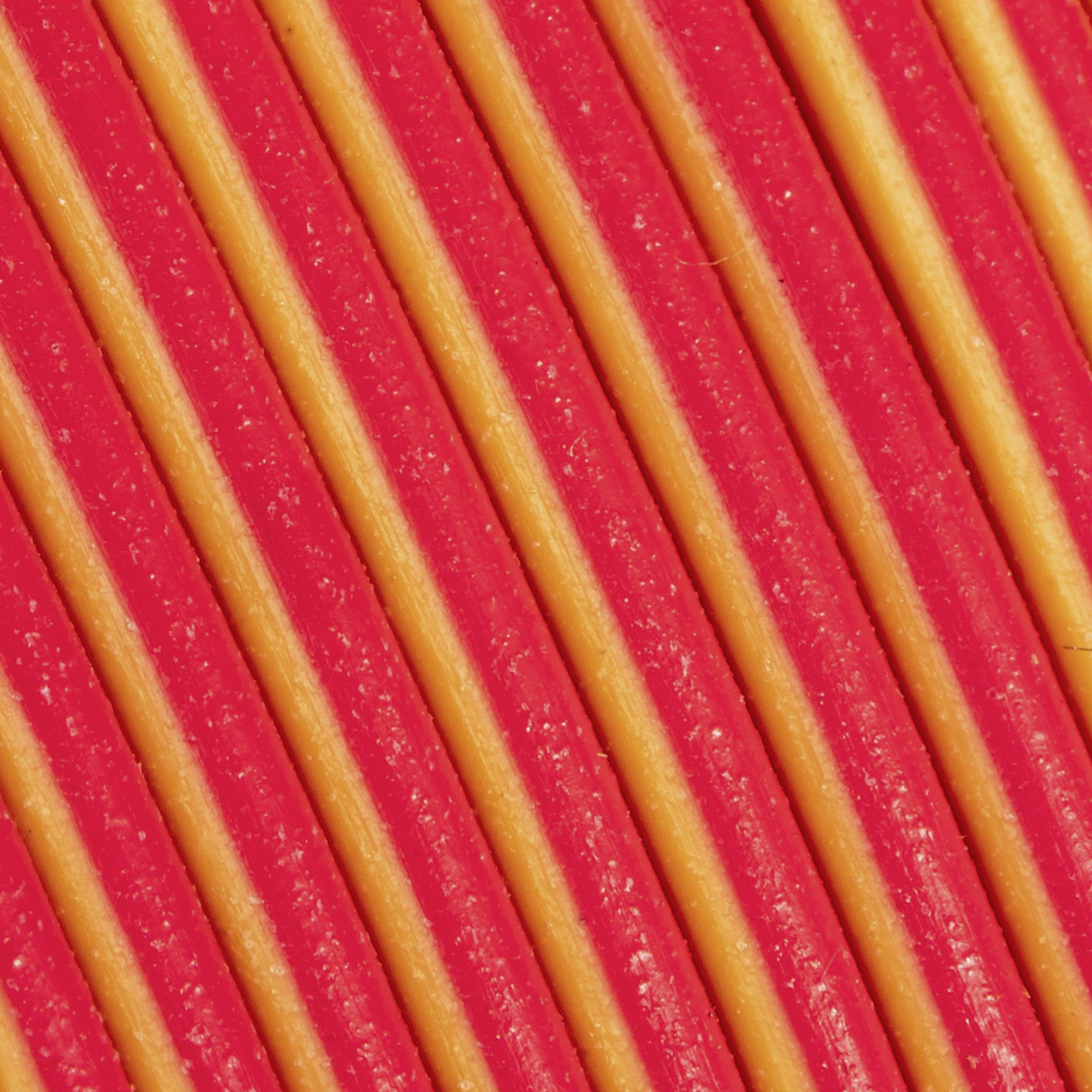 Gros plan de pâtes jaune-rouge disposées parallèlement les unes aux autres et formant un motif rayé.