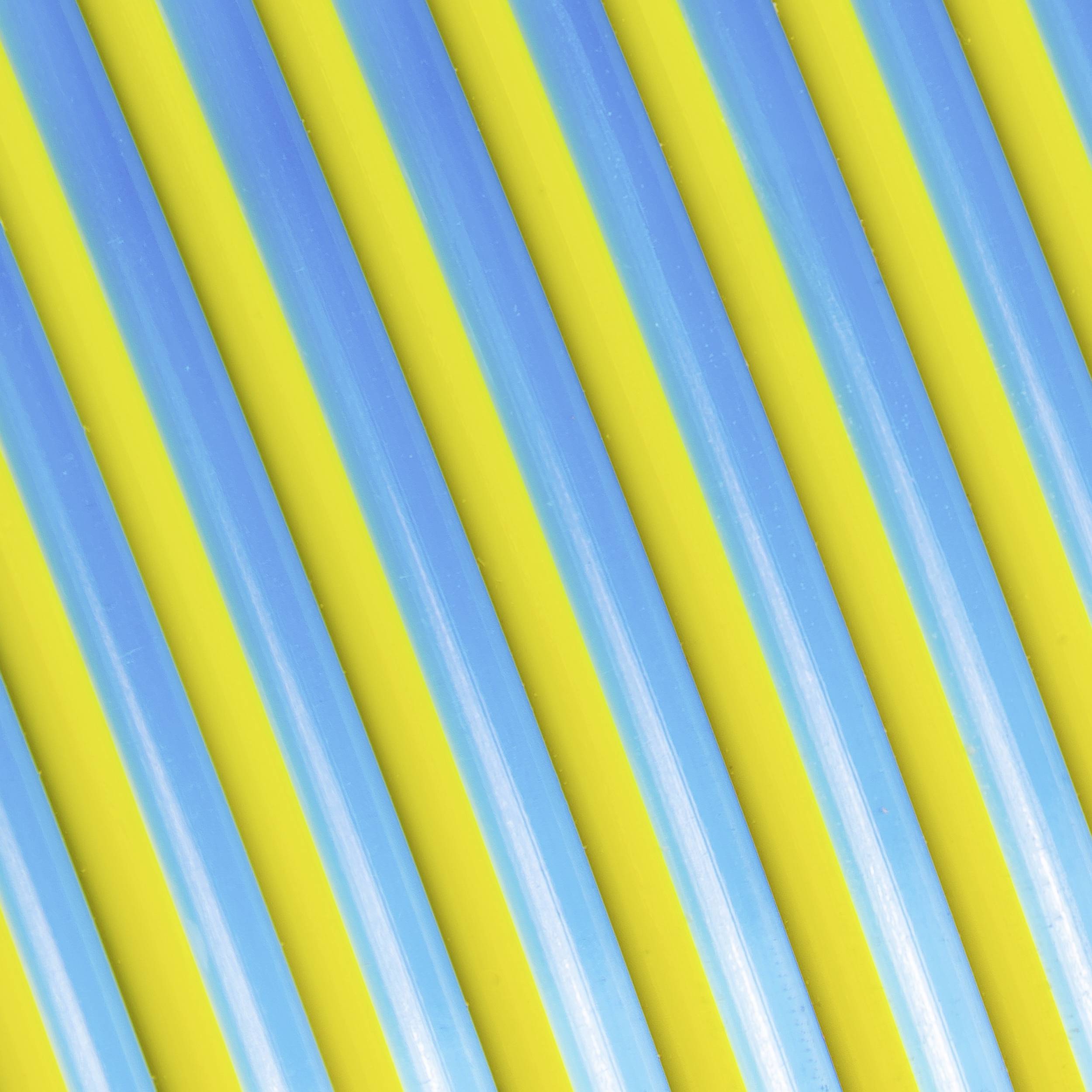Gros plan de pailles en plastique rayées multicolores en bleu et jaune, disposées en parallèle.