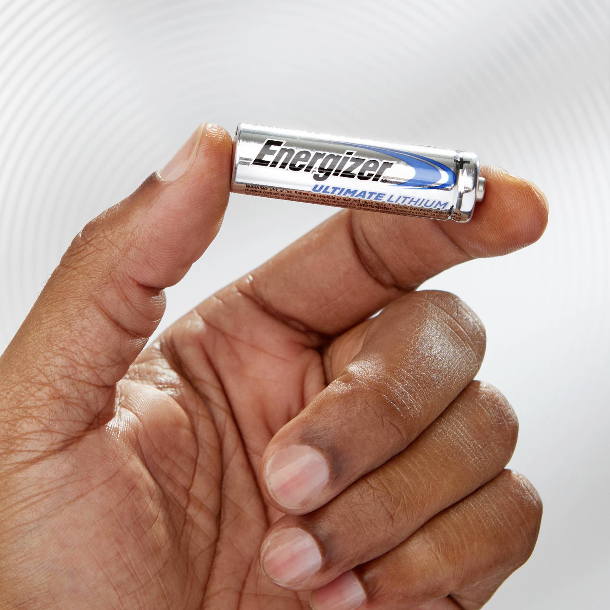 Une main tient une pile Energizer Ultimate Lithium devant un fond neutre.