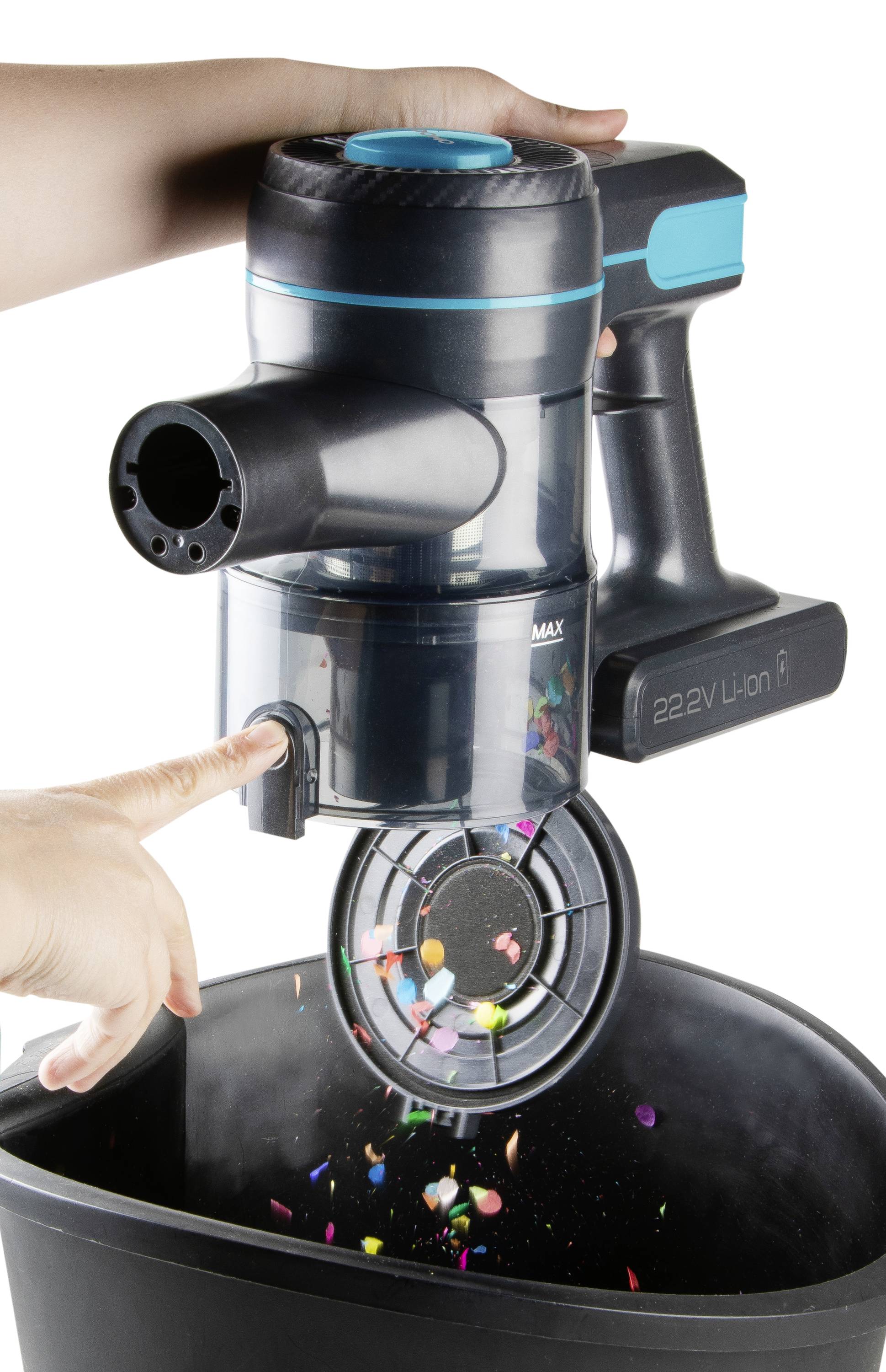 Une main actionne un aspirateur à main au-dessus d'une poubelle, vidant des saletés et des particules colorées.