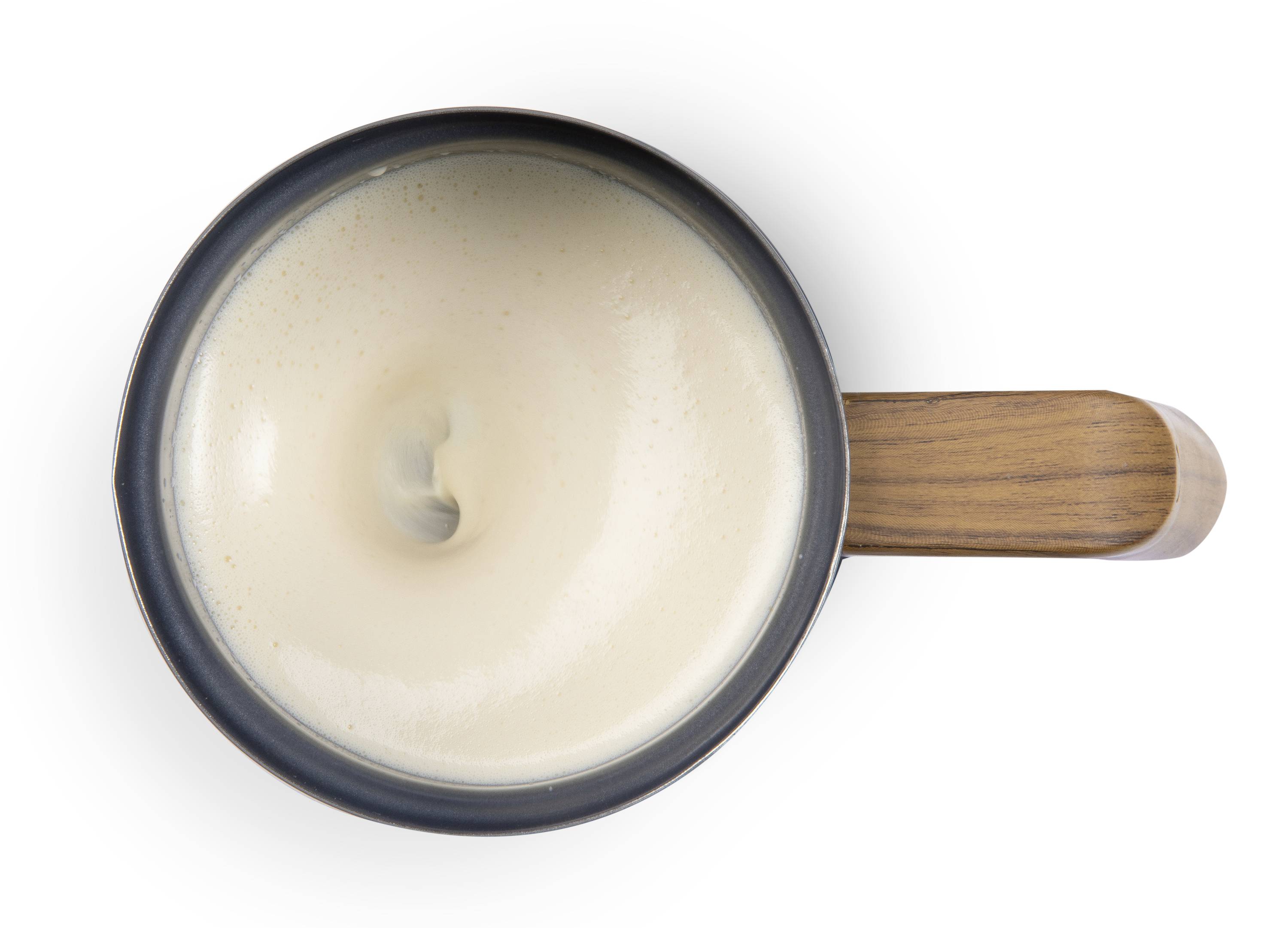 Une tasse de café noir avec un tourbillon de mousse, vue de dessus, avec une poignée en bois à droite.
