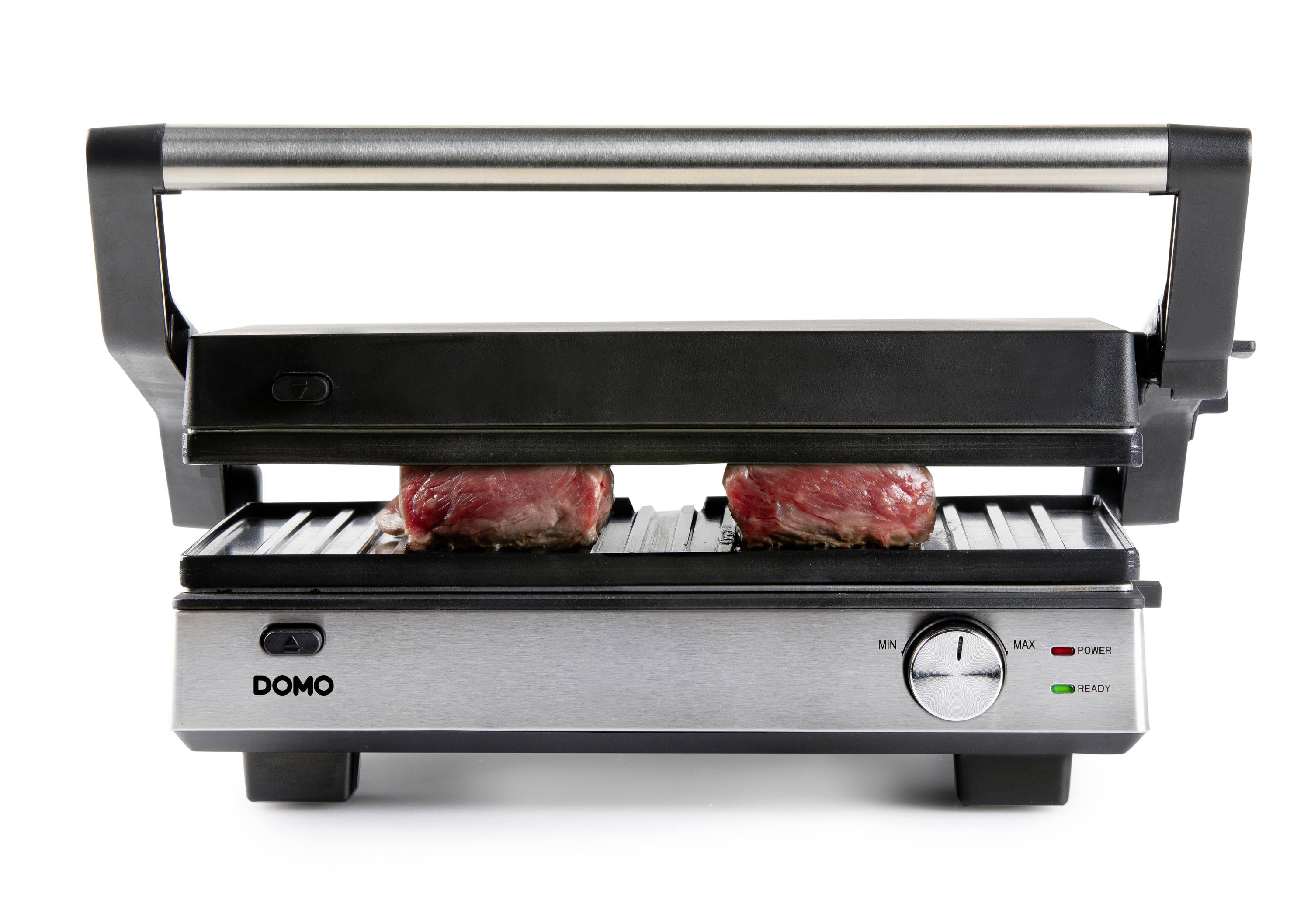 Un grill de contact avec deux morceaux de viande crue sur la surface de cuisson, sous la plaque supérieure fermée.