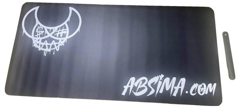 Tapis noir avec un motif de visage stylisé blanc en haut à gauche et l'inscription 'ABSIMA.COM' en bas à droite.