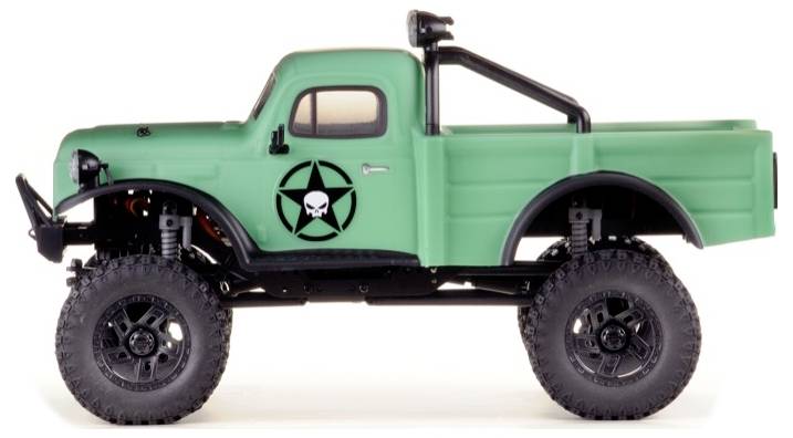 Un camion jouet vert de style militaire, avec de grandes roues tout-terrain et un autocollant représentant un crâne et une étoile sur la portière.