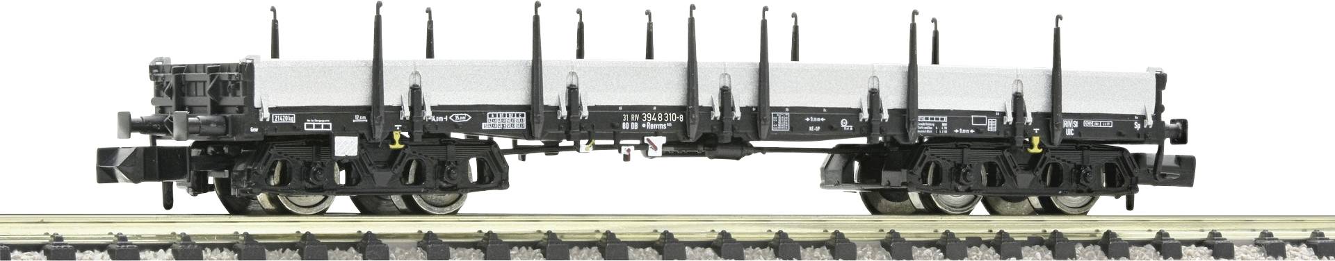 Un wagon de marchandises noir avec une bâche blanche est stationné sur une voie ferrée, adapté au transport de marchandises volumineuses et plates.