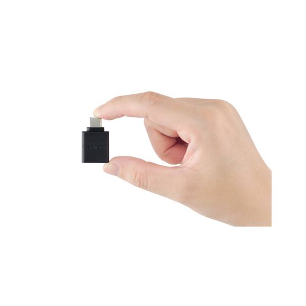 Une main tient un petit adaptateur USB noir avec un port USB-C.