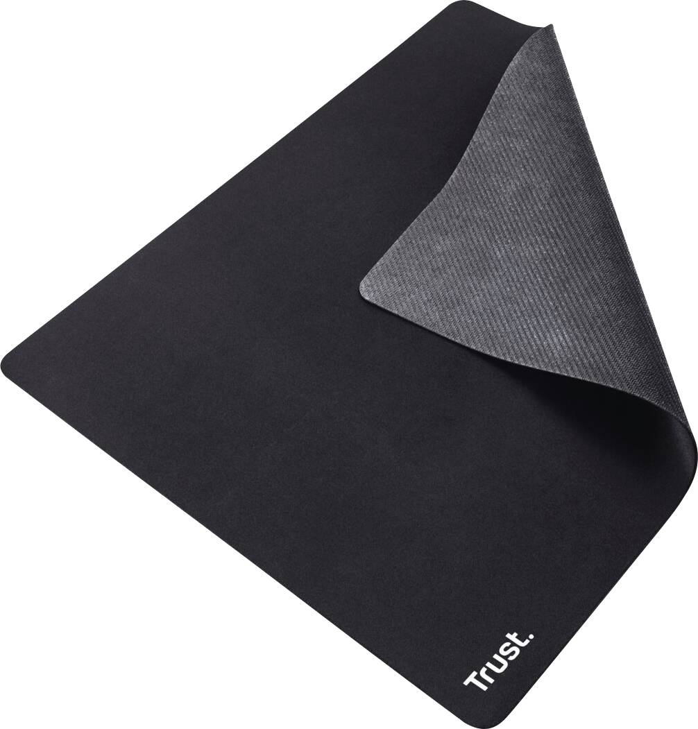 Un tapis de souris noir et carré avec un coin plié, montrant l'envers. En bas à droite se trouve le logo blanc 'Trust'.