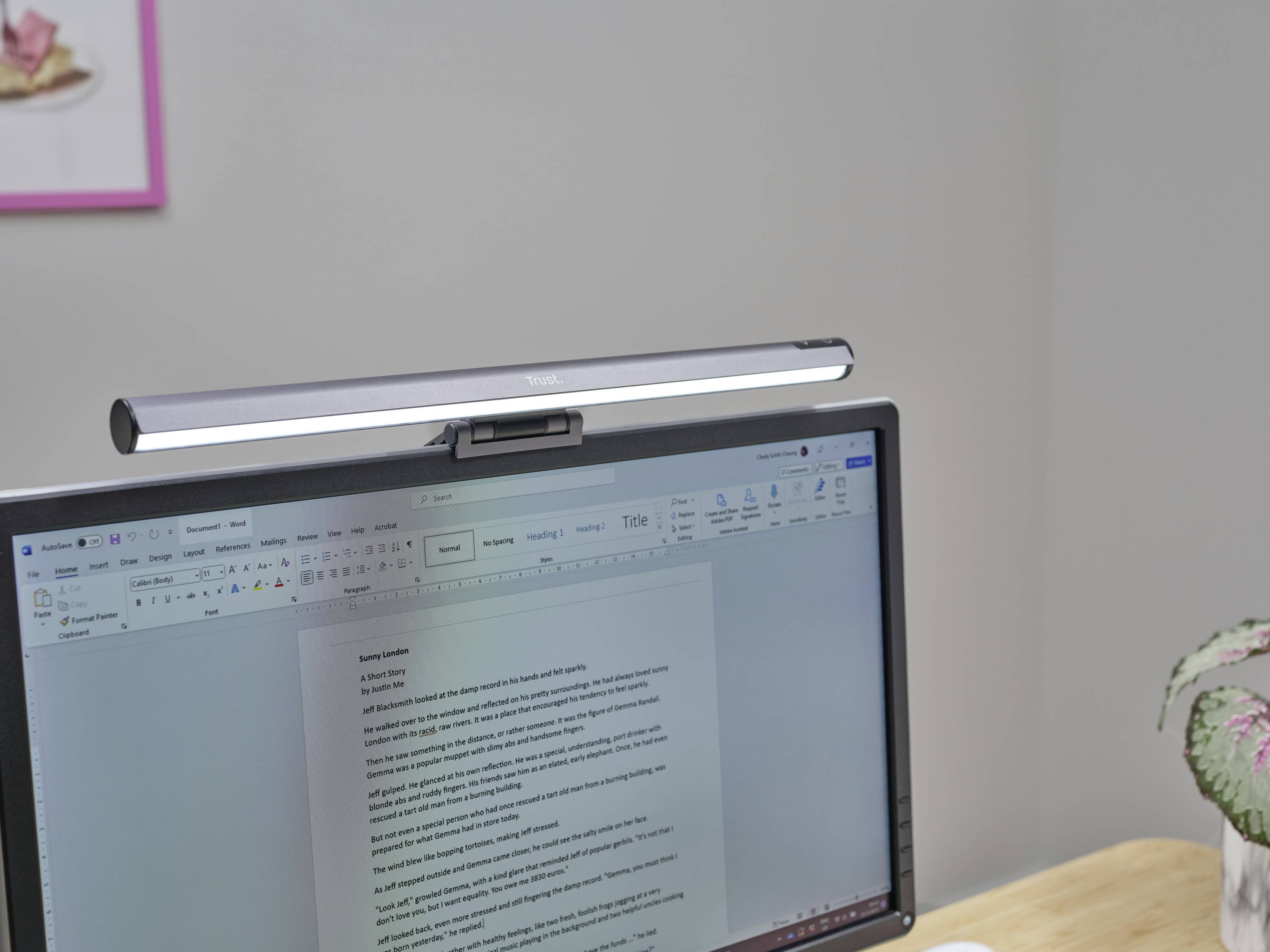 Une lampe de bureau est fixée en haut d'un écran d'ordinateur affichant un document de traitement de texte. Arrière-plan détaillé flou.