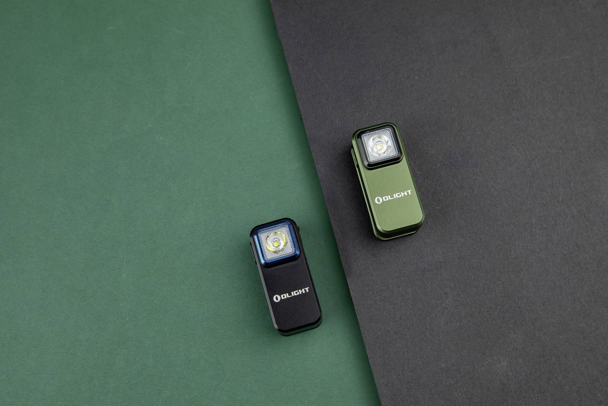 Deux petites lampes de poche sur un fond vert et noir, l'une bleue, l'autre verte, toutes deux portant le logo 'Olight'.