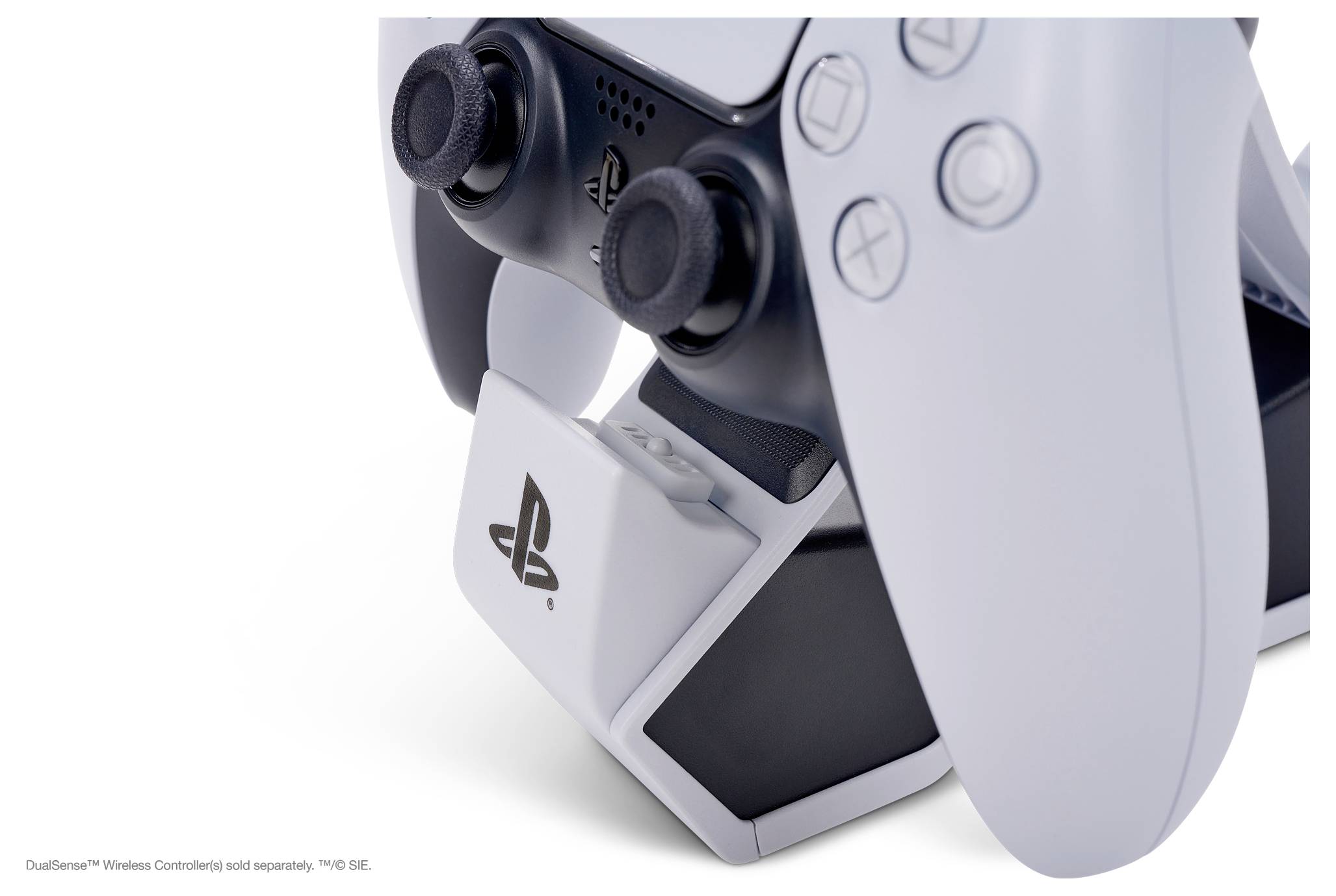 Gros plan sur une manette de jeu blanche sans fil posée dans sa station de charge. La manette présente un design ergonomique doté de plusieurs boutons.