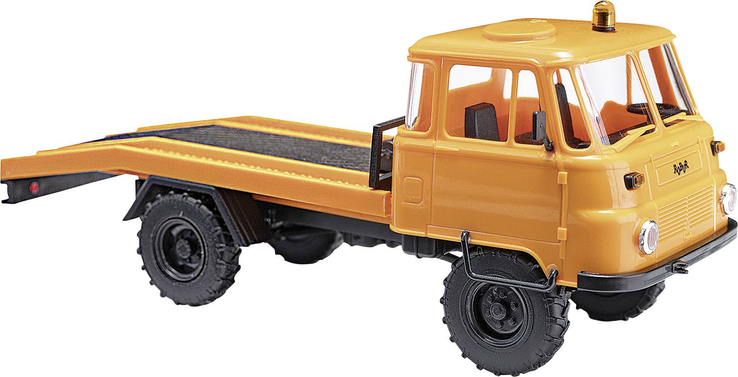 Un camion-jouet orange avec plateau, portant la marque 'IFA', est posé sur un fond blanc.