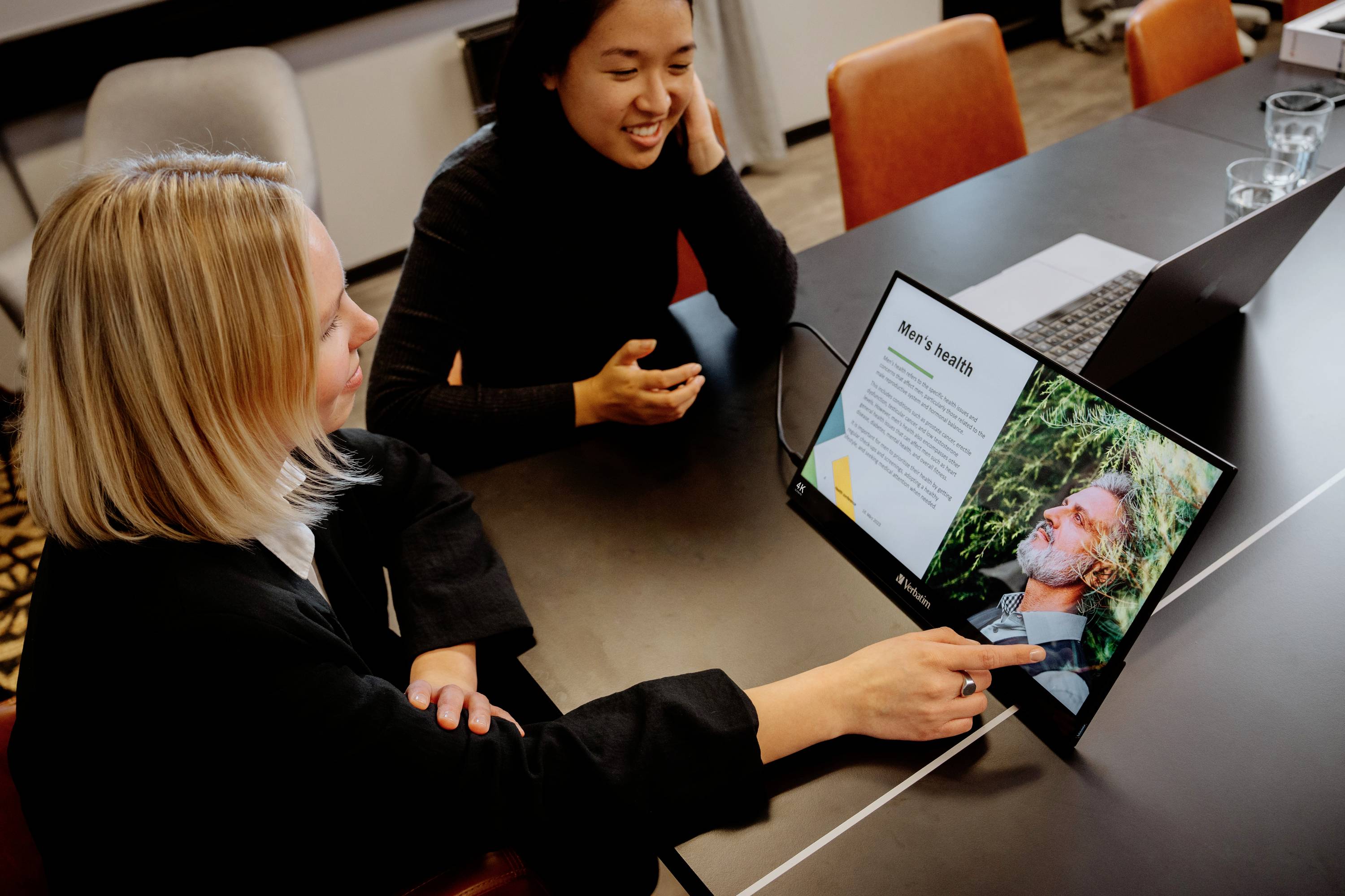 Deux personnes sont dans une salle de réunion et regardent l'écran d'un ordinateur portable affichant une présentation sur les 