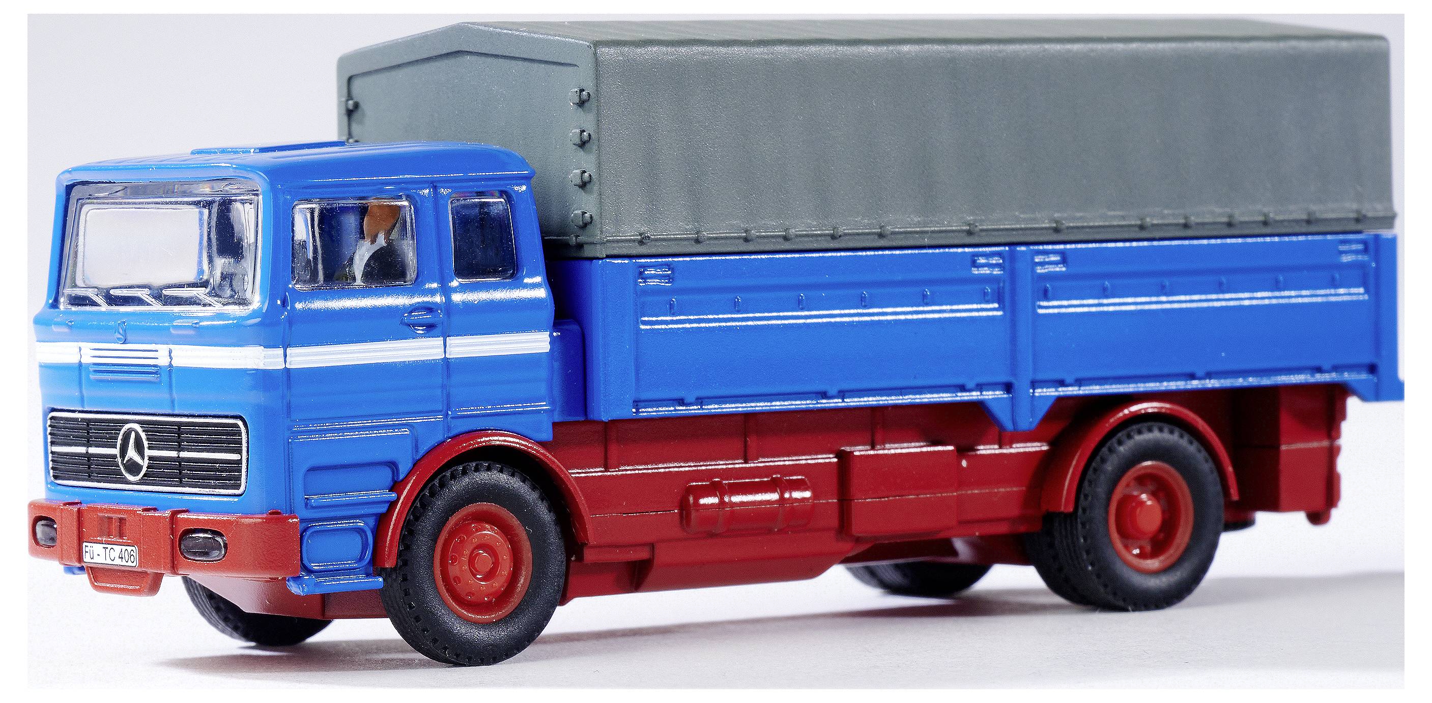 Un camion miniature en bleu et rouge avec une bâche grise, typique des anciens camions européens.