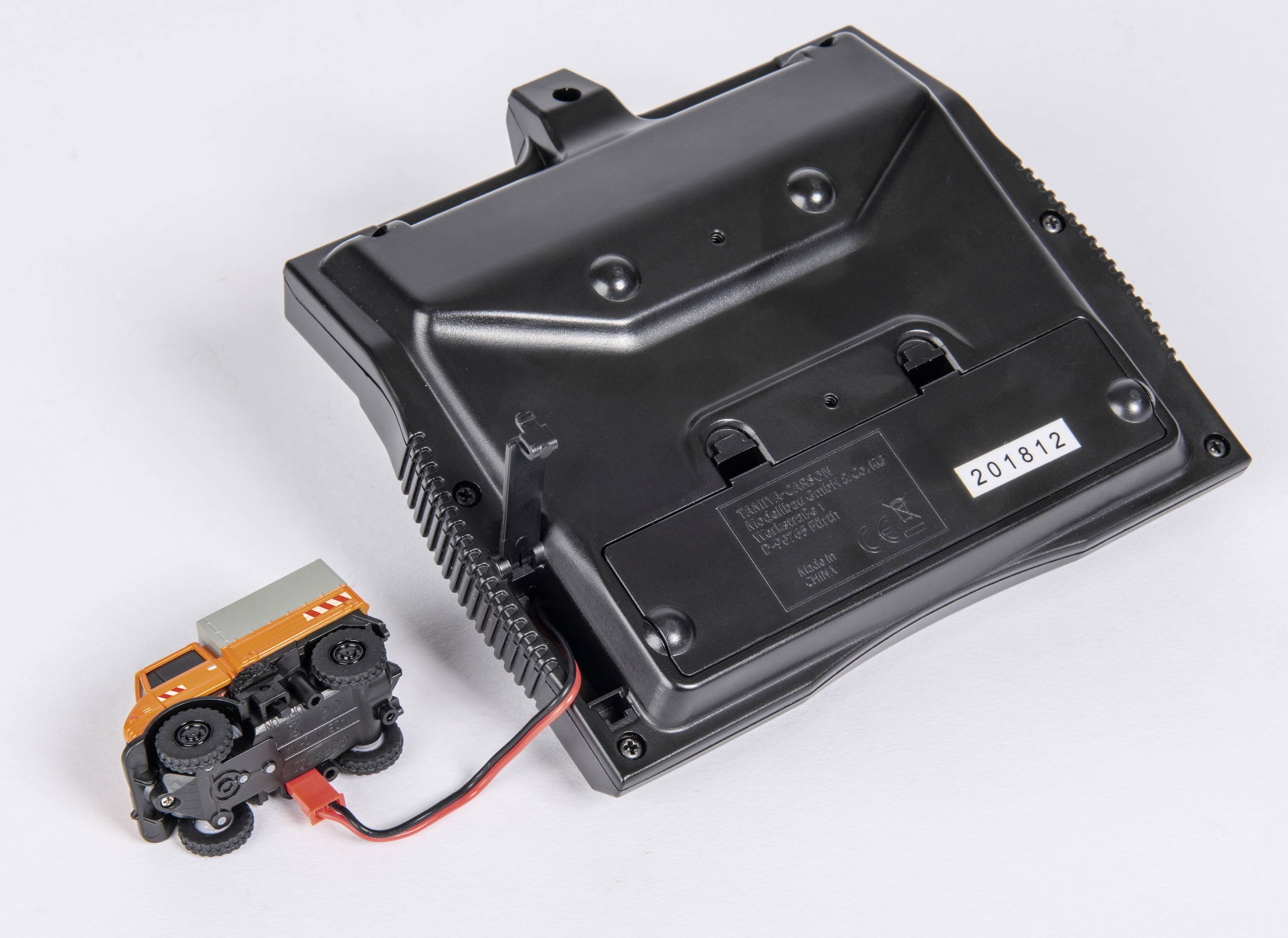 Une petite voiture miniature reliée par un câble à un appareil électronique noir. L'appareil porte un numéro de série.