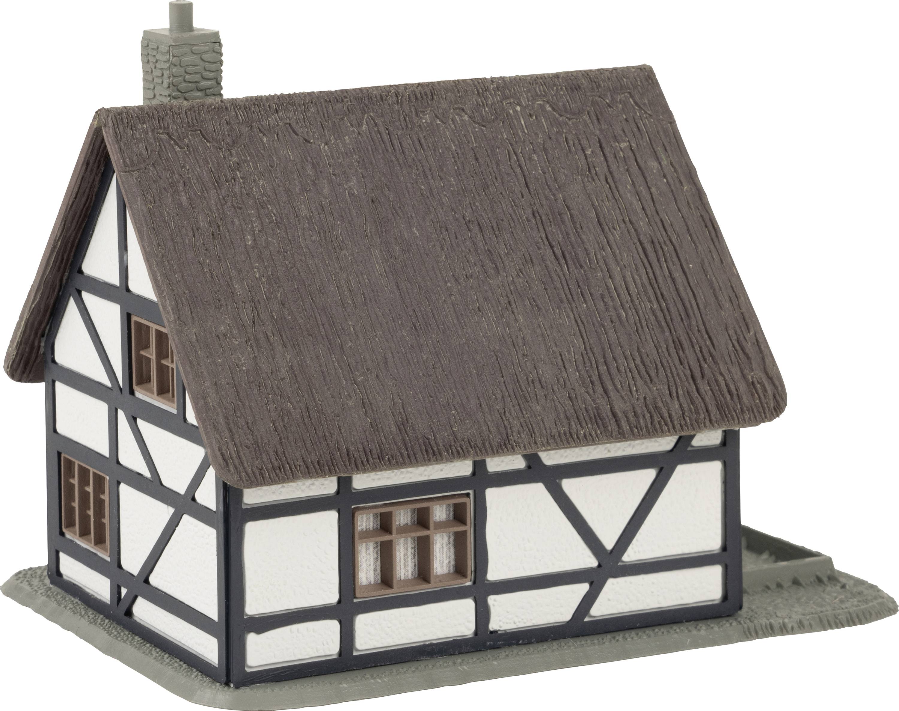 Modèle de maison à colombages avec toit de chaume et cheminée, murs blancs avec des poutres en bois sombres.