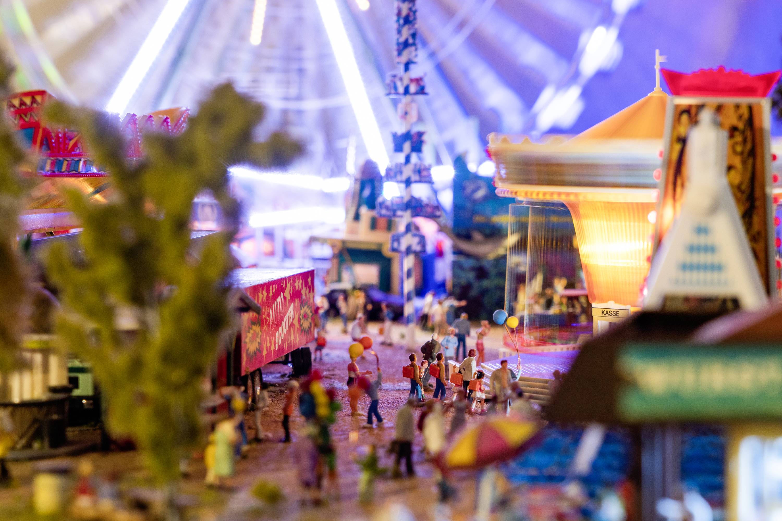 Une mini-fête foraine avec des trains miniatures, des manèges et des personnages en mouvement. Illuminée de couleurs vives et animée d'une ambiance bourdonnante.