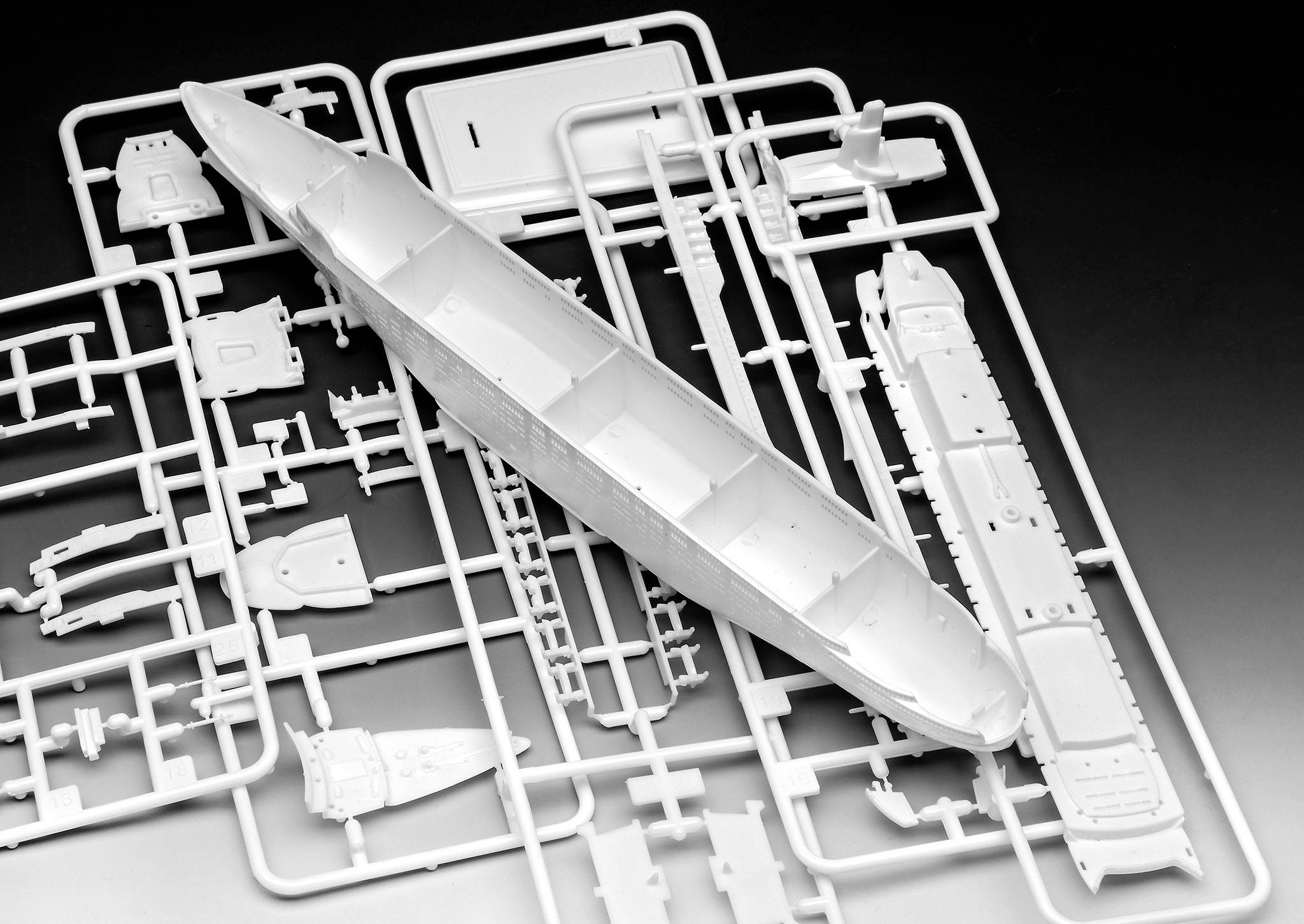 Kit de modélisme naval en plastique avec différentes pièces sur un cadre, prêt à être assemblé.