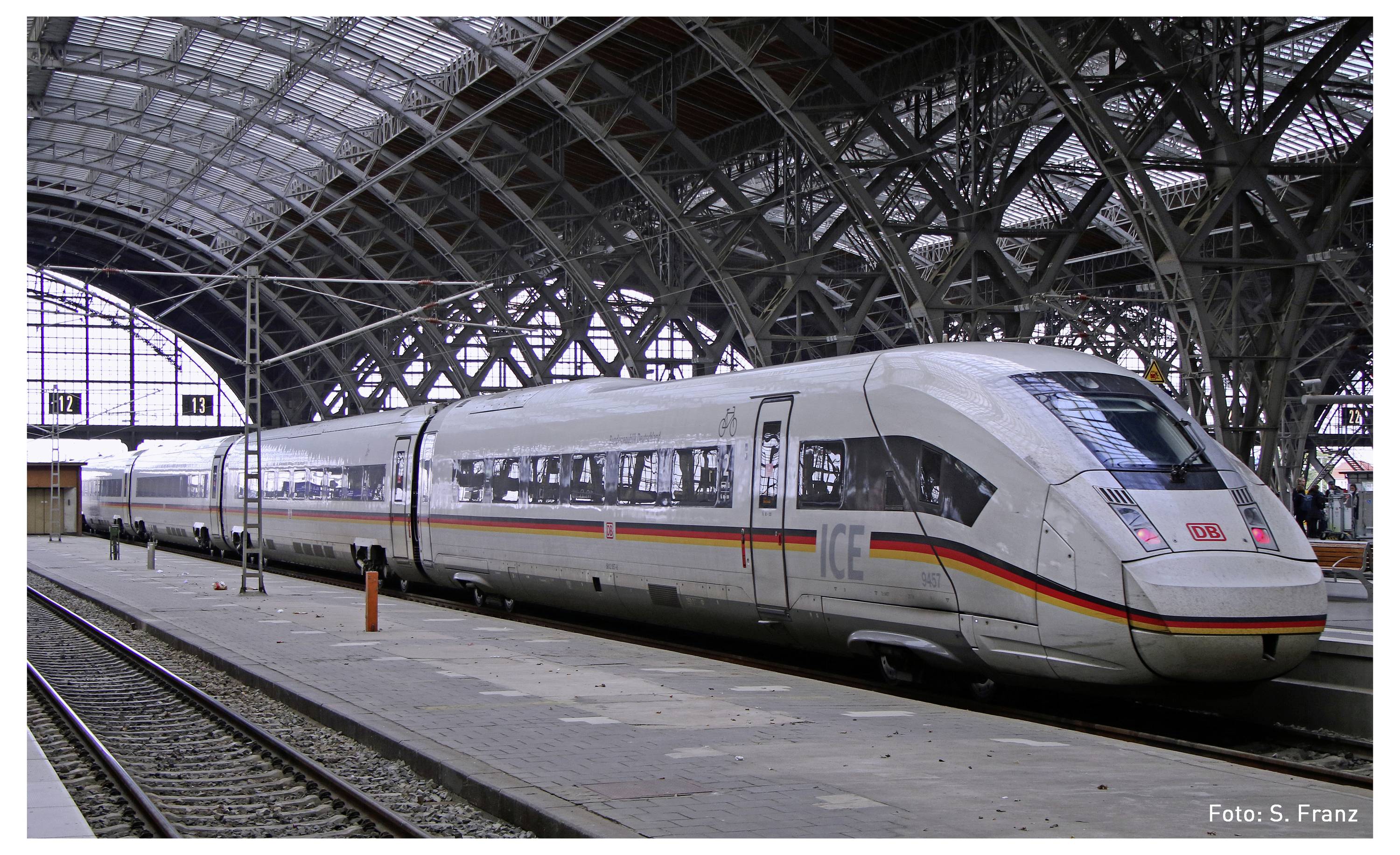 Train à grande vitesse ICE stationné sur le quai dans une gare couverte. Le véhicule est blanc avec des bandes rouges et jaunes.