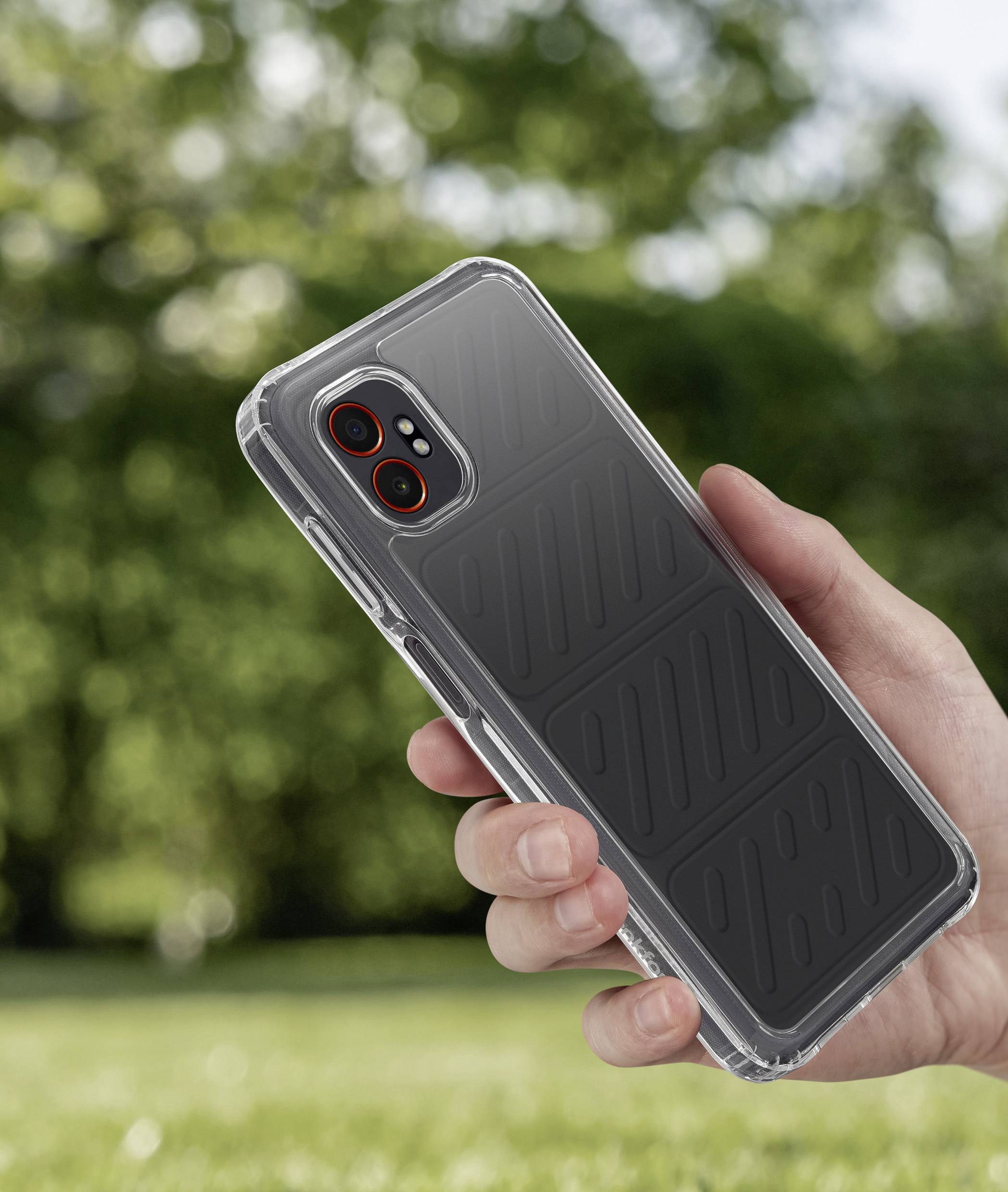 Une main tient un smartphone dans un étui noir à l'extérieur, avec de la verdure floue en arrière-plan.