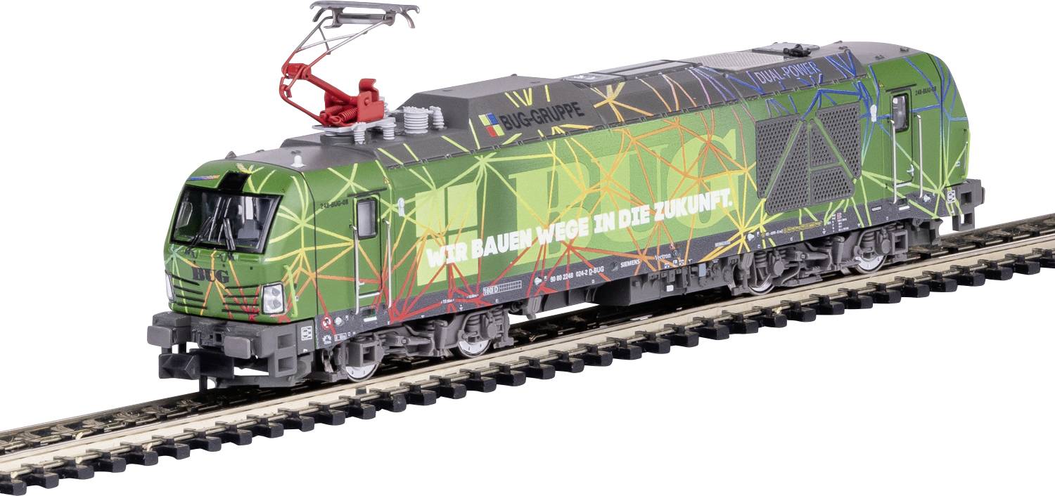 Une locomotive vert et multicolore portant l'inscription « Nous construisons des chemins vers l'avenir », roule sur une voie ferrée, entourée de motifs géométriques.