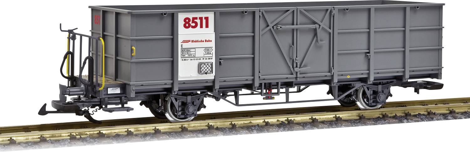 Un wagon de marchandises gris portant le numéro '8511' est stationné sur une voie ferrée. Le wagon est équipé de poignées jaunes et de roues noires.